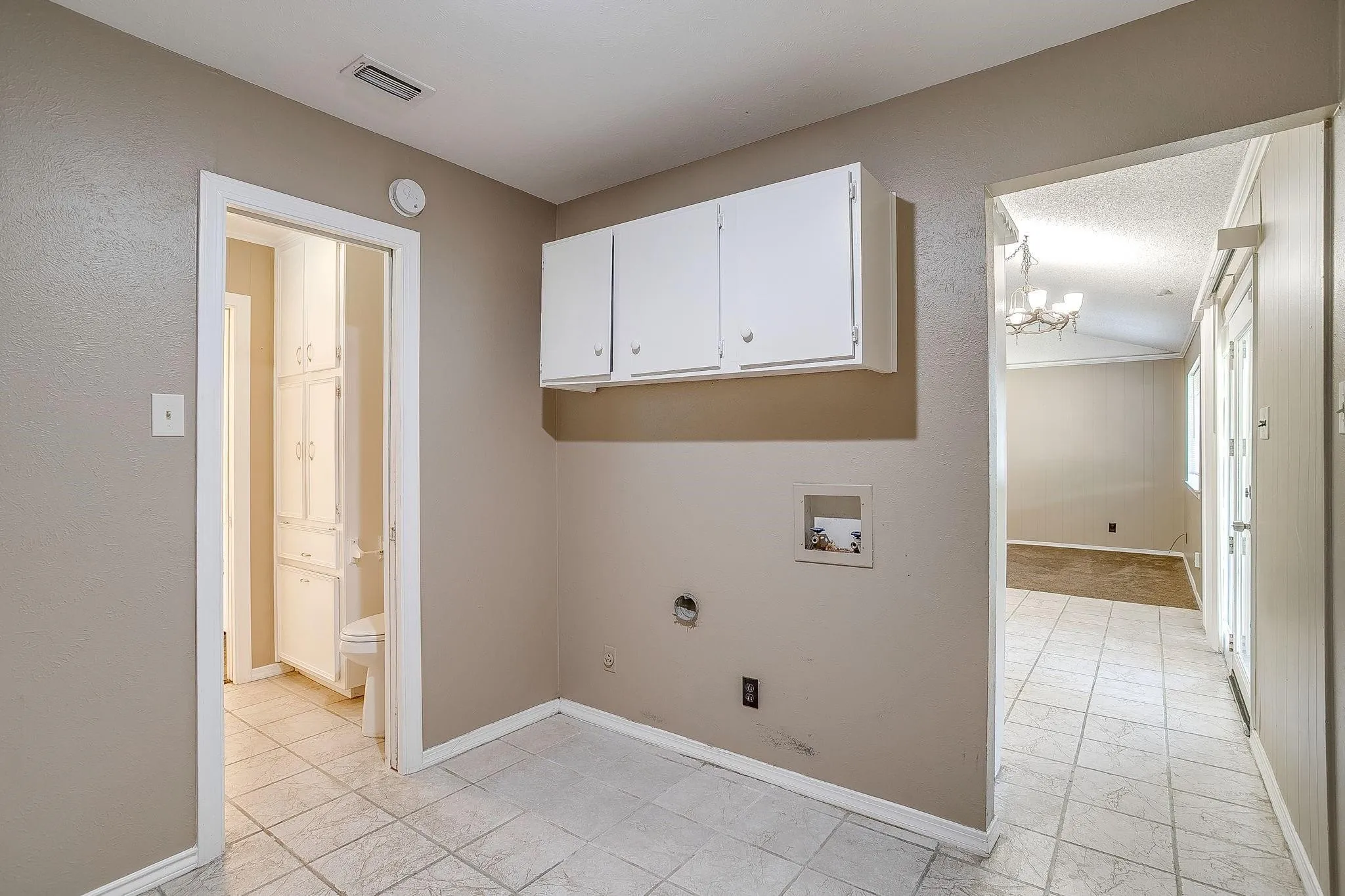 Built-in overhead white cabinetry, tile flooring, and dedicated appliance hookups
