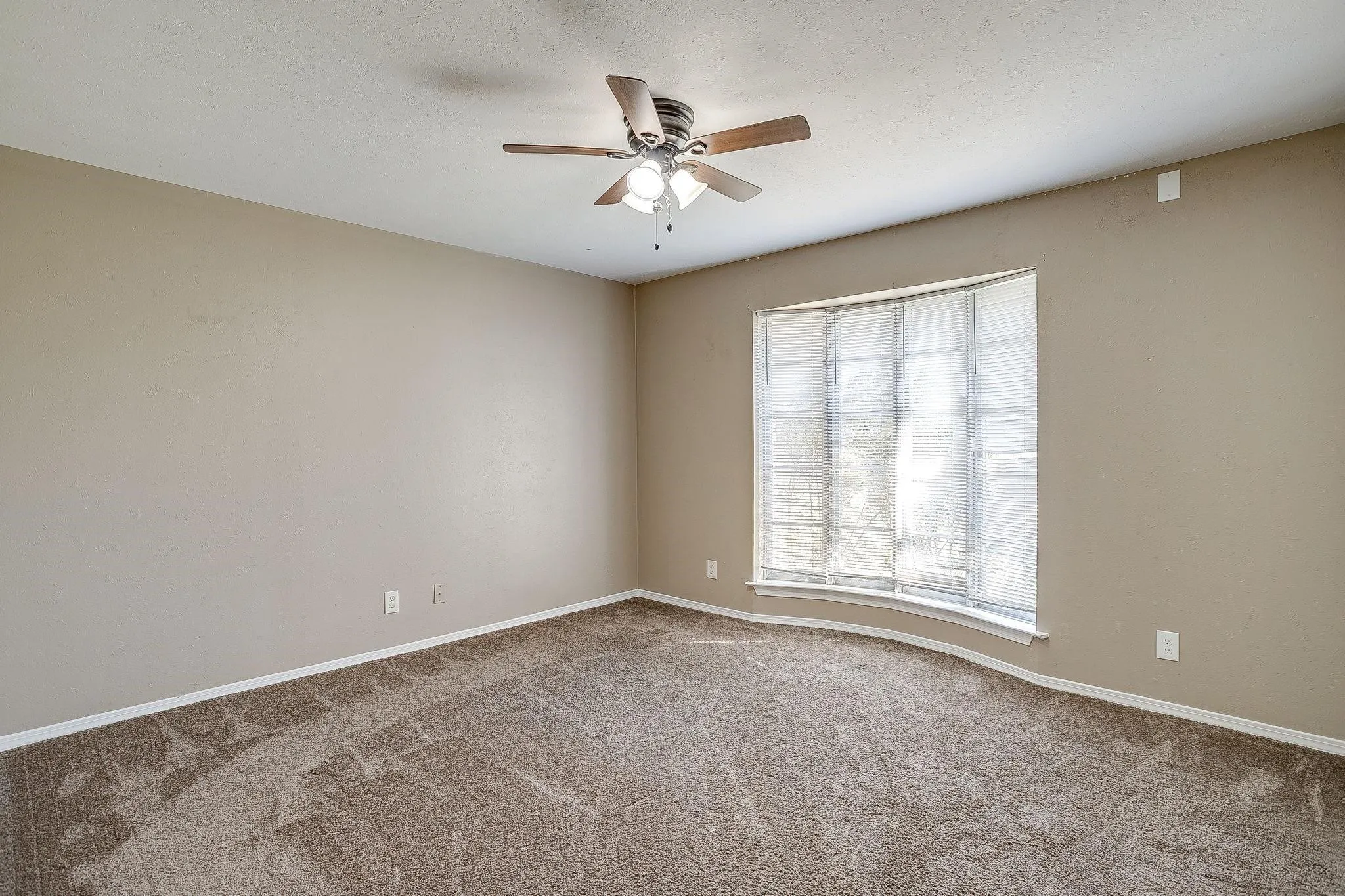Recessed window with multiple panels, ceiling fan with integrated lighting, and neutral carpeting