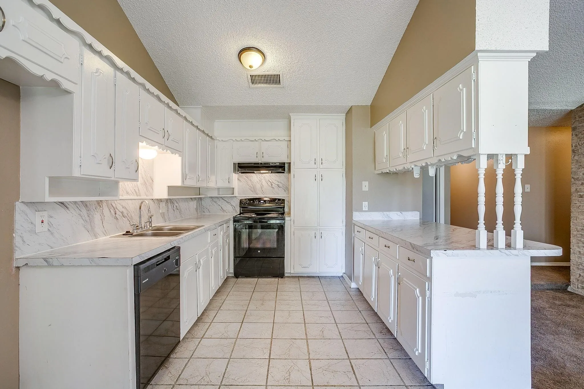 Kitchen featuring white cabinetry, stone-look countertops with integrated backsplash, tile flooring, and a black range