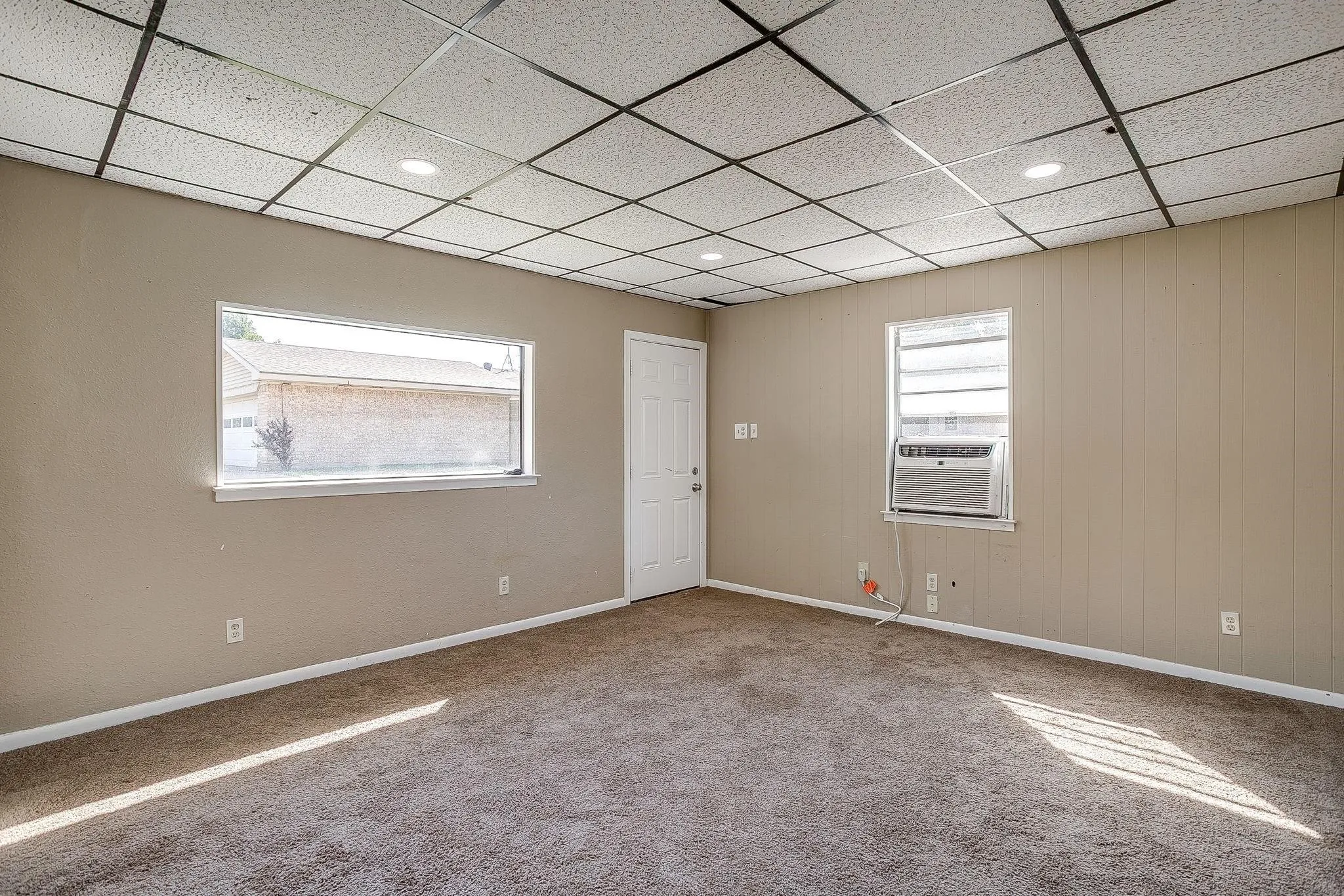 Recessed lighting with grid ceiling, beige walls, and carpet flooring
