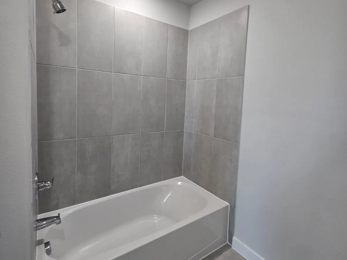 Bathtub with gray subway tile surround and chrome fixtures