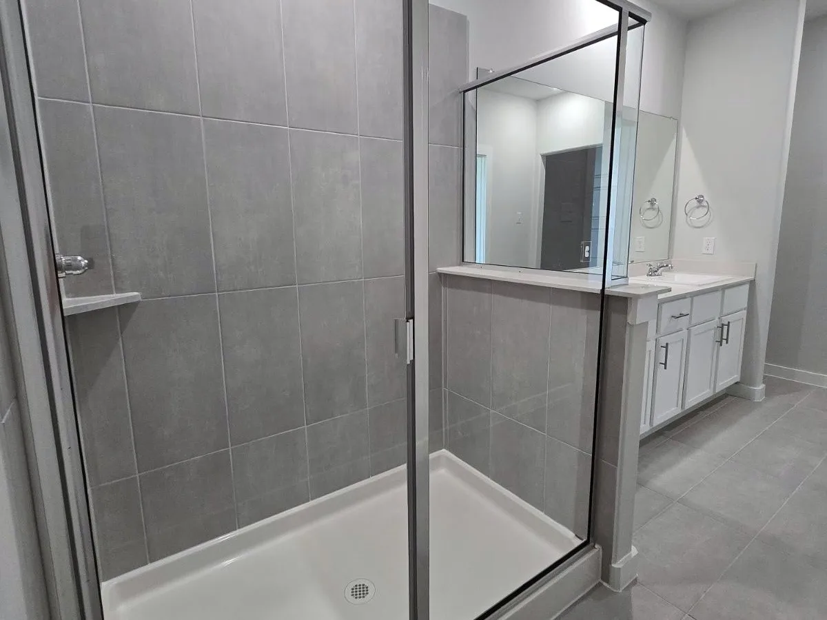 Walk-in shower with clear glass enclosure and integrated shelf