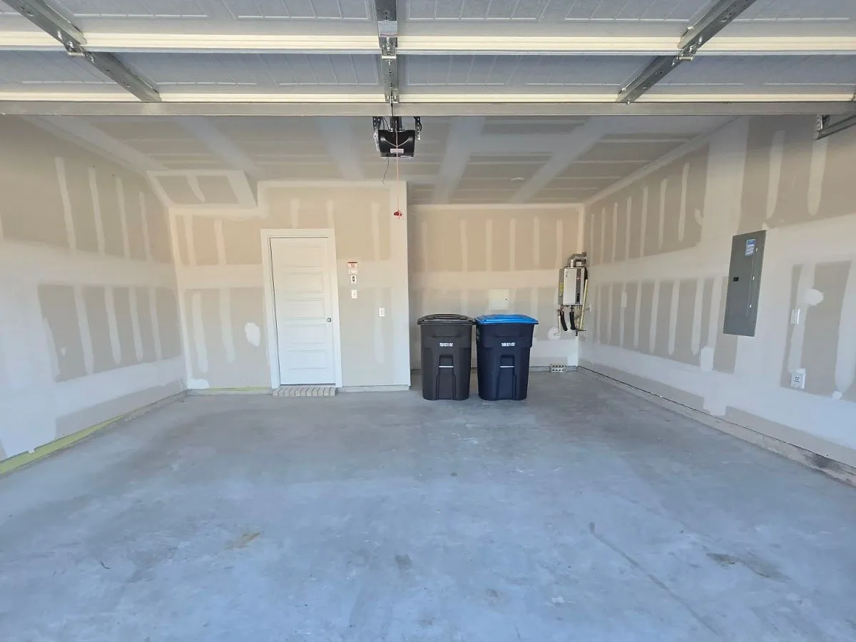 Interior garage space featuring a concrete floor, an overhead garage door mechanism, and a side-entry door