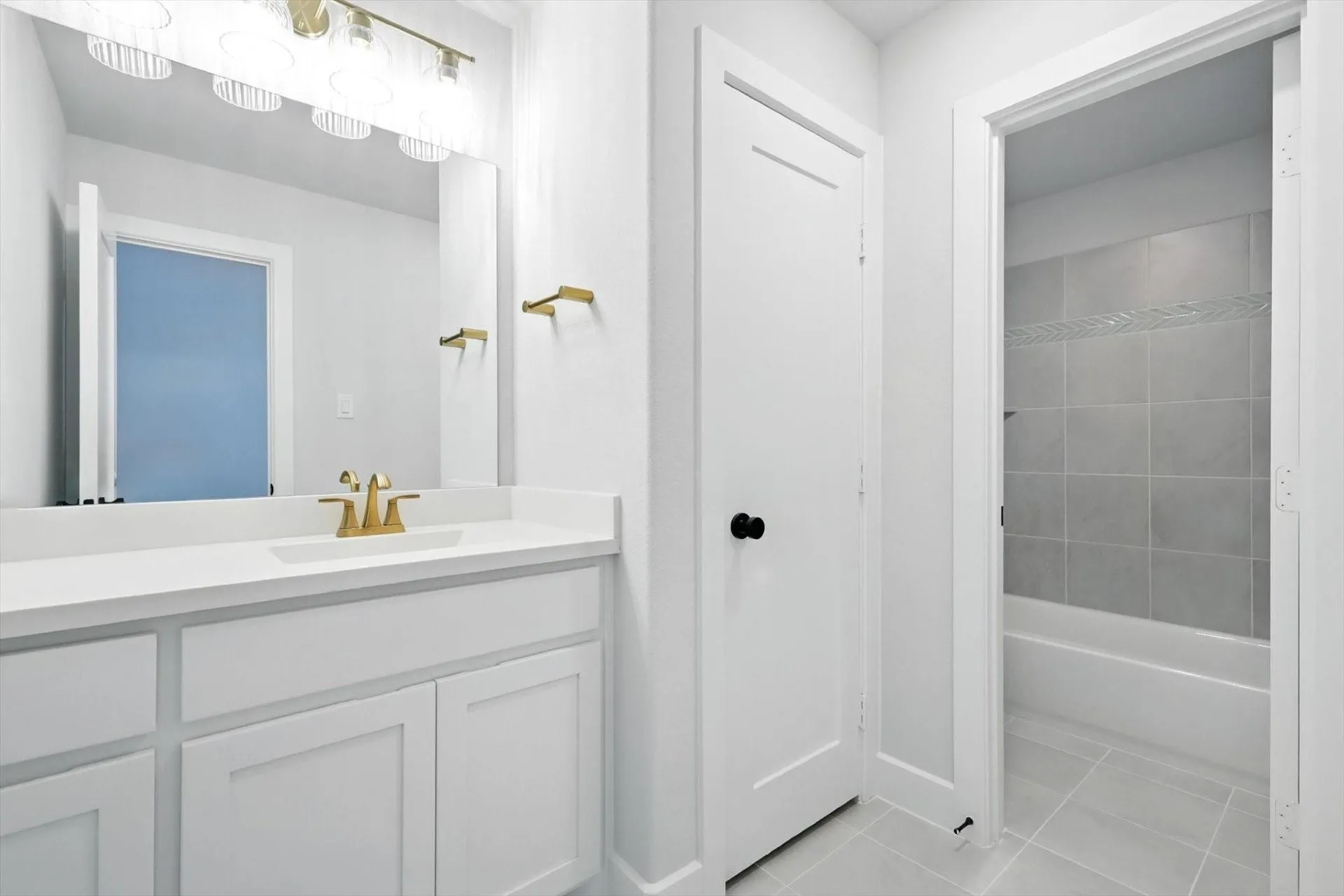 Vanity with a white countertop and gold-finish faucet, framed mirror, and built-in lighting