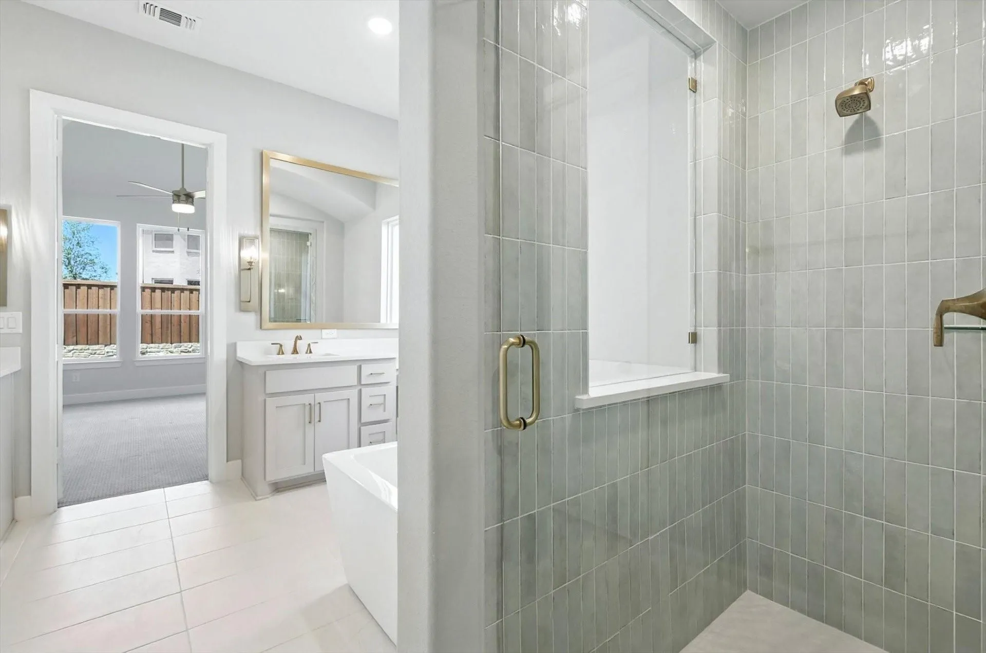 Walk-in shower with vertical tile detailing, an expansive vanity with double sinks, a freestanding soaking tub, and tile flooring