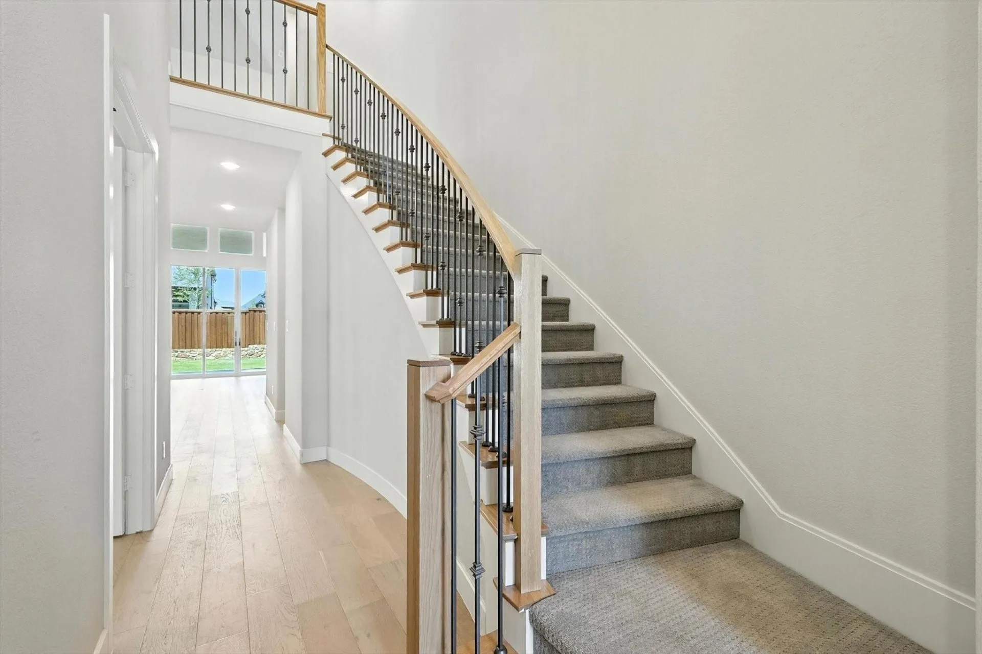 Curved staircase featuring wood handrails and wrought iron balusters