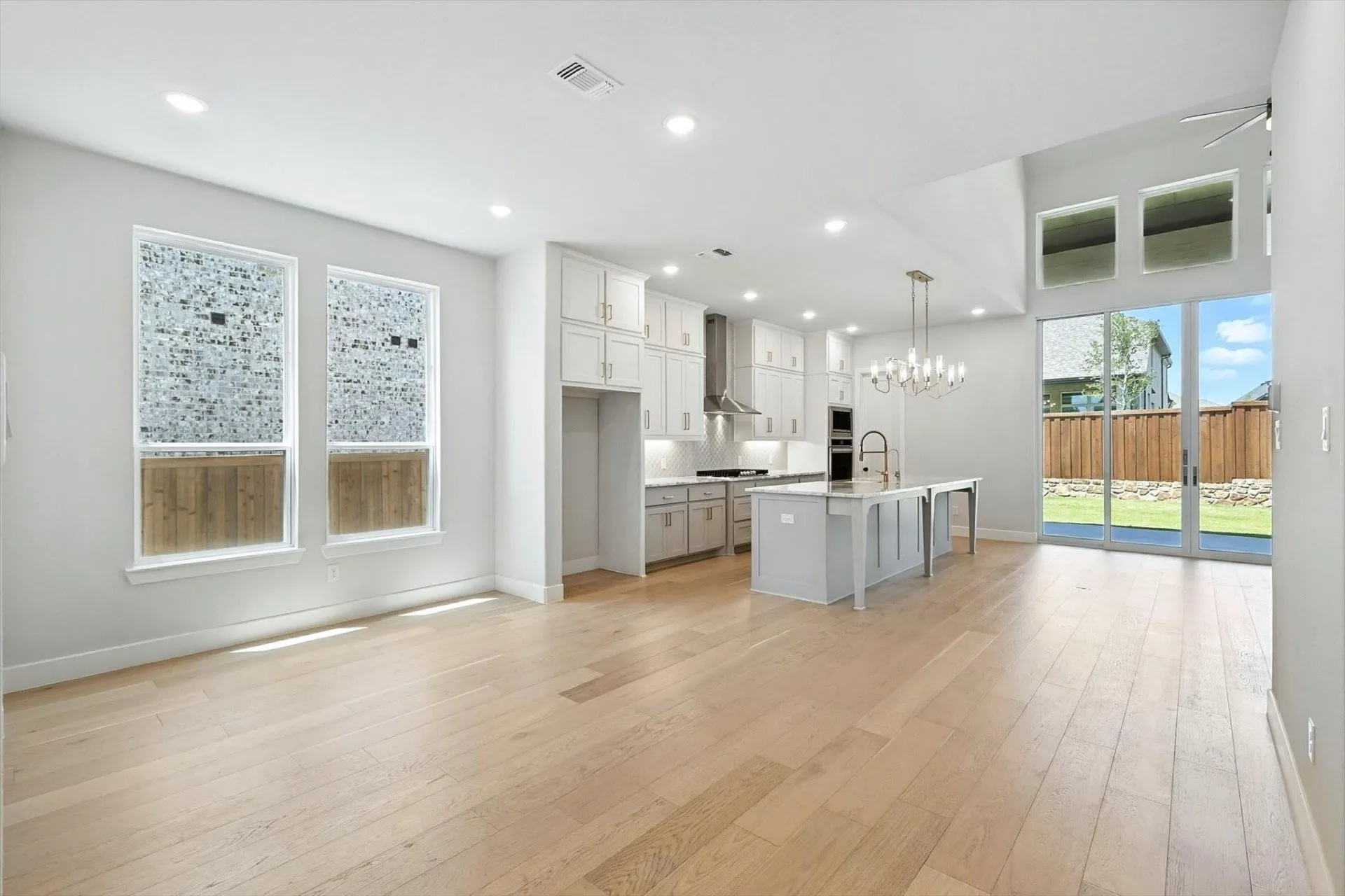 Open-concept living area featuring light wood-finish flooring, recessed lighting, and a kitchen island with seating