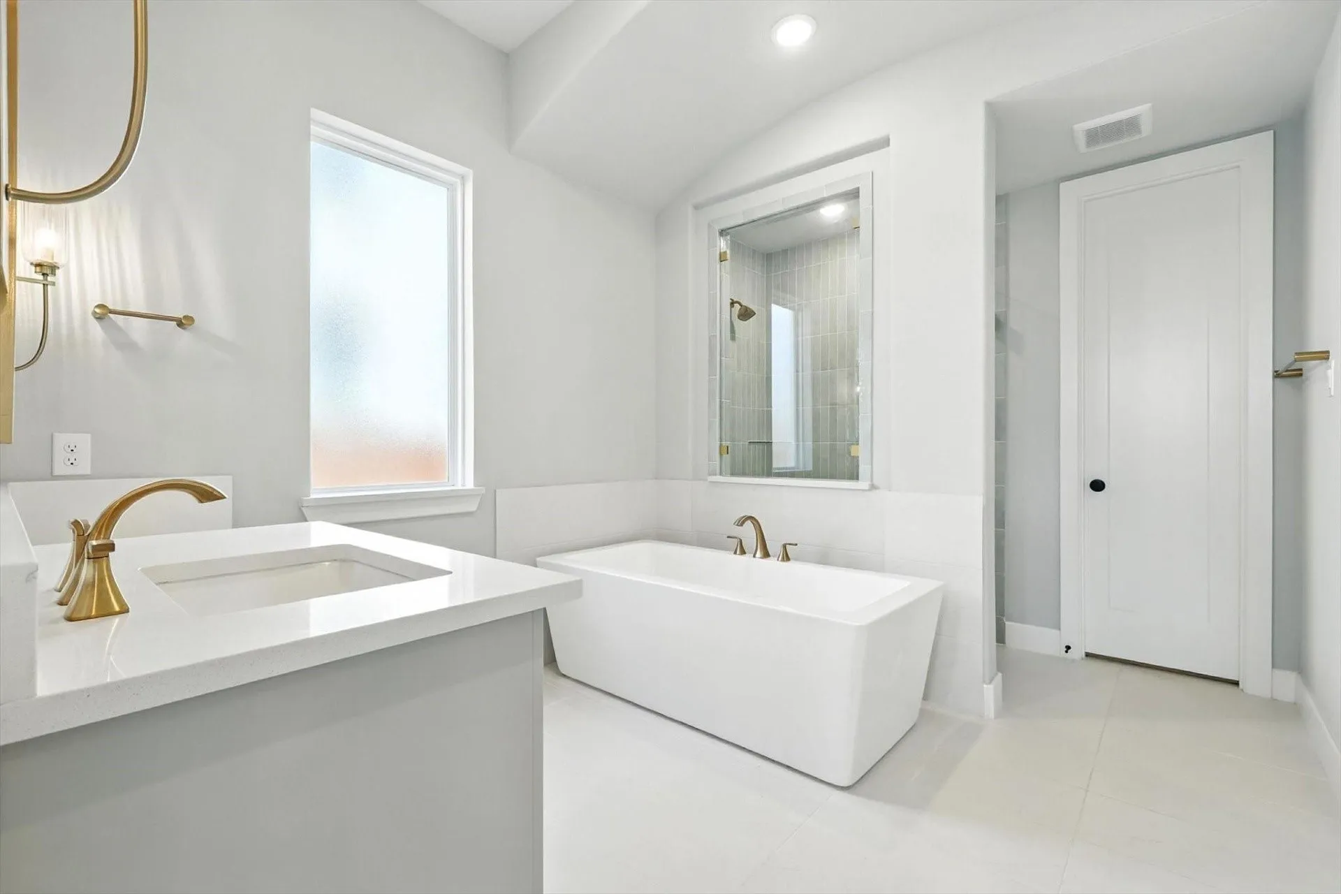 Freestanding soaking tub, walk-in shower with glass enclosure, single vanity with integrated sink, quartz countertop, and gold-finish fixtures