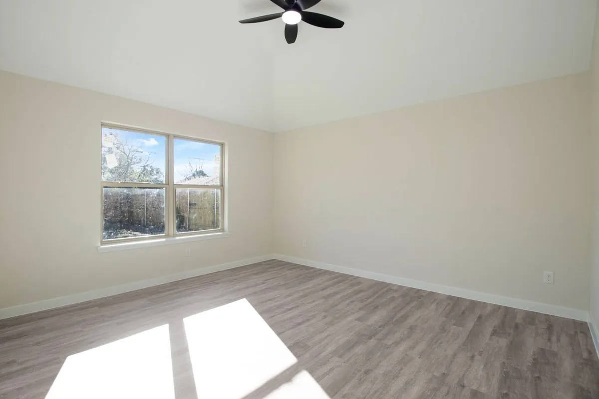Vaulted ceiling with a ceiling fan, light-toned walls, and wood-finish flooring
