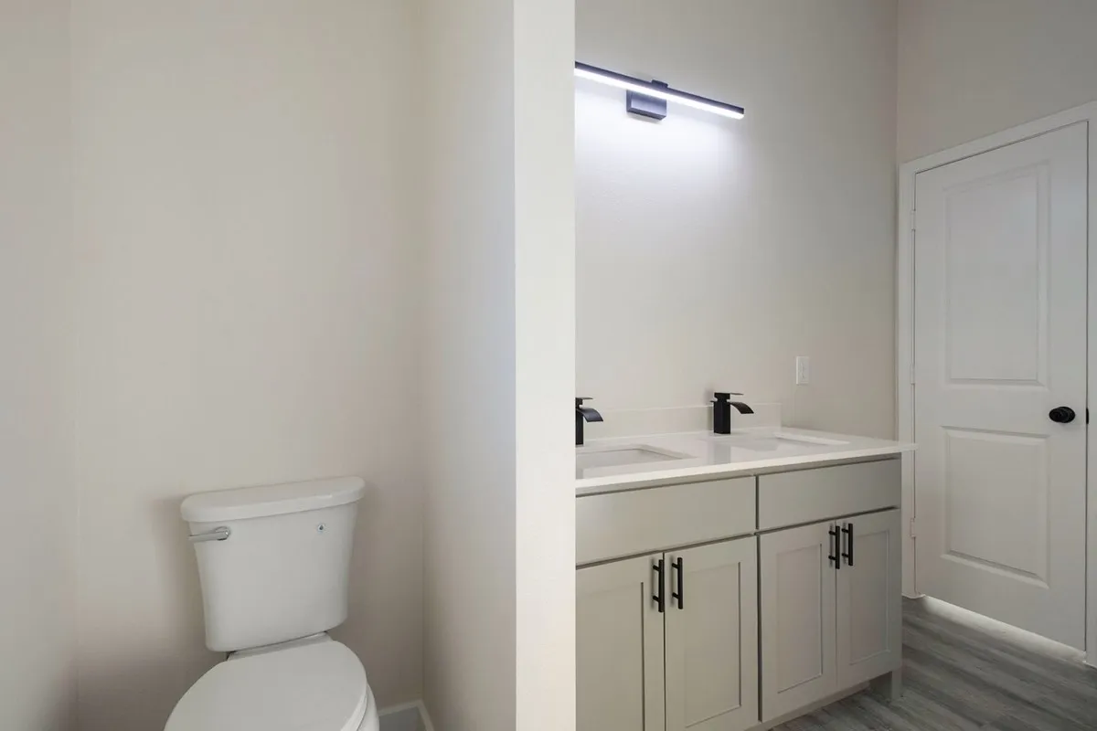 Dual vanity with matte black faucets, light gray cabinetry, and a light-toned countertop