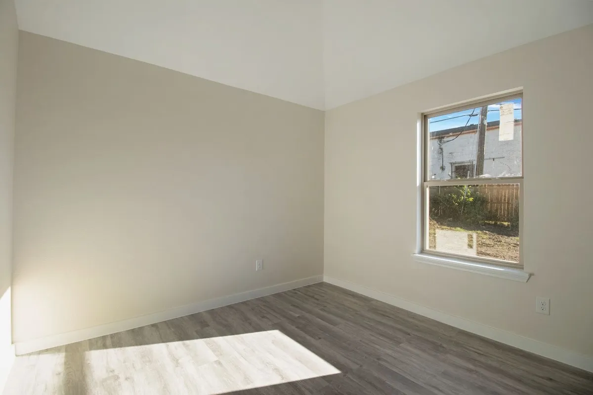Neutral-toned walls, wood-finish flooring, and a single window with white trim