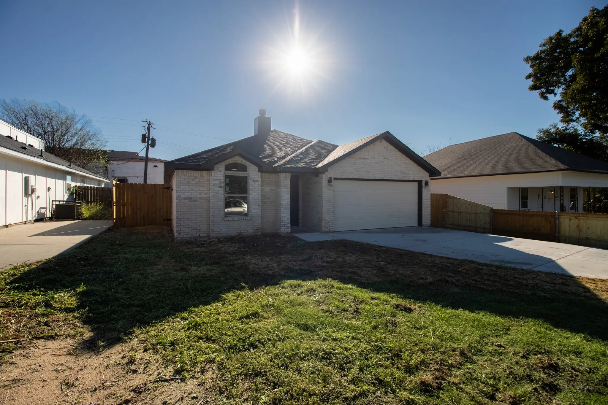 Light brick exterior, arched window, attached garage, concrete driveway, wood privacy fence