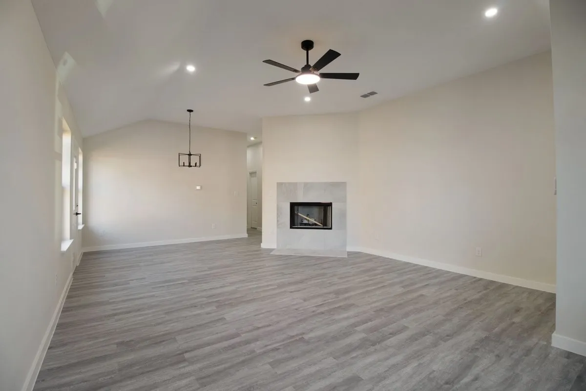 Vaulted ceilings, recessed lighting, and a modern ceiling fan illuminate this expansive room