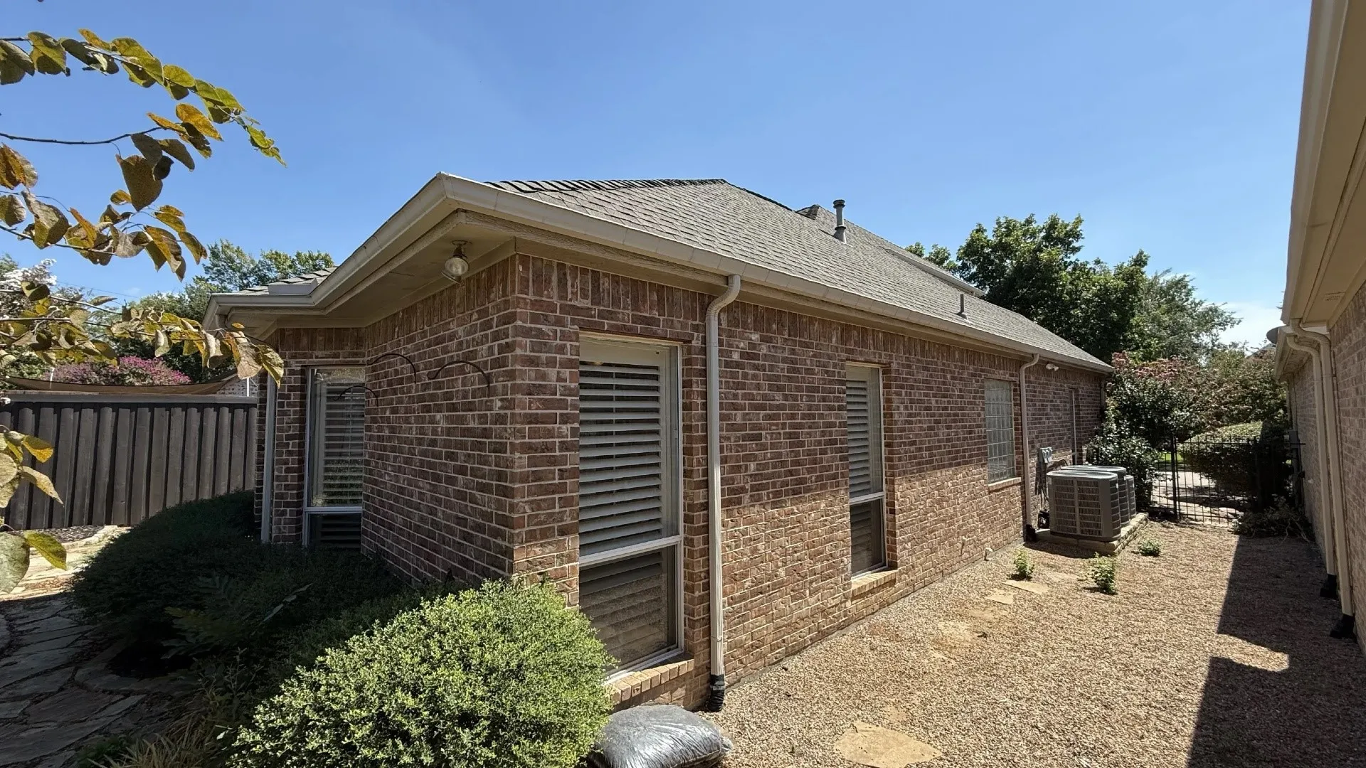 Brick exterior with multiple windows, a sloped roof, and a gravel pathway