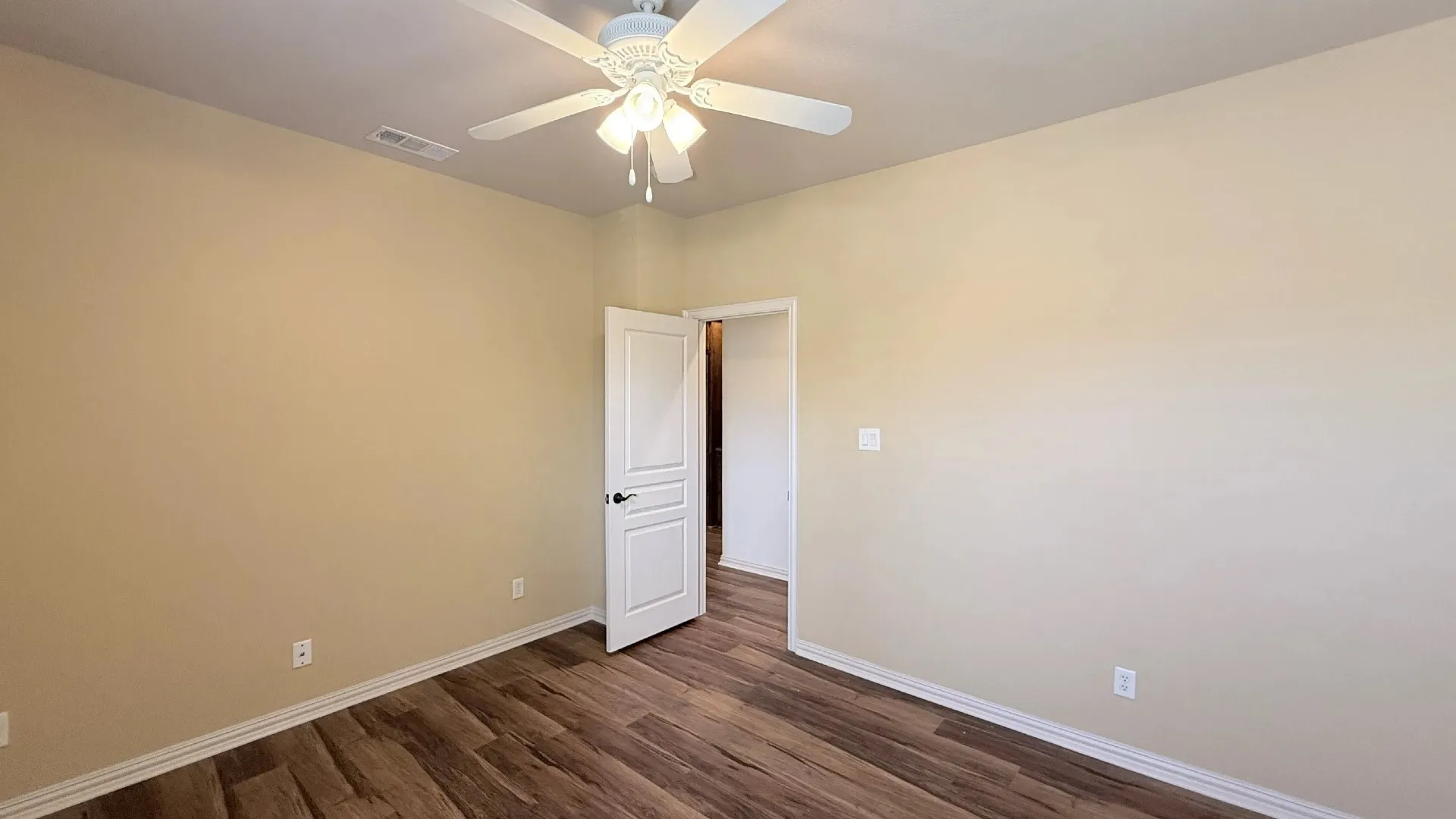 Wood-finish flooring, light neutral wall tones, white trim, and a ceiling fan with integrated lighting