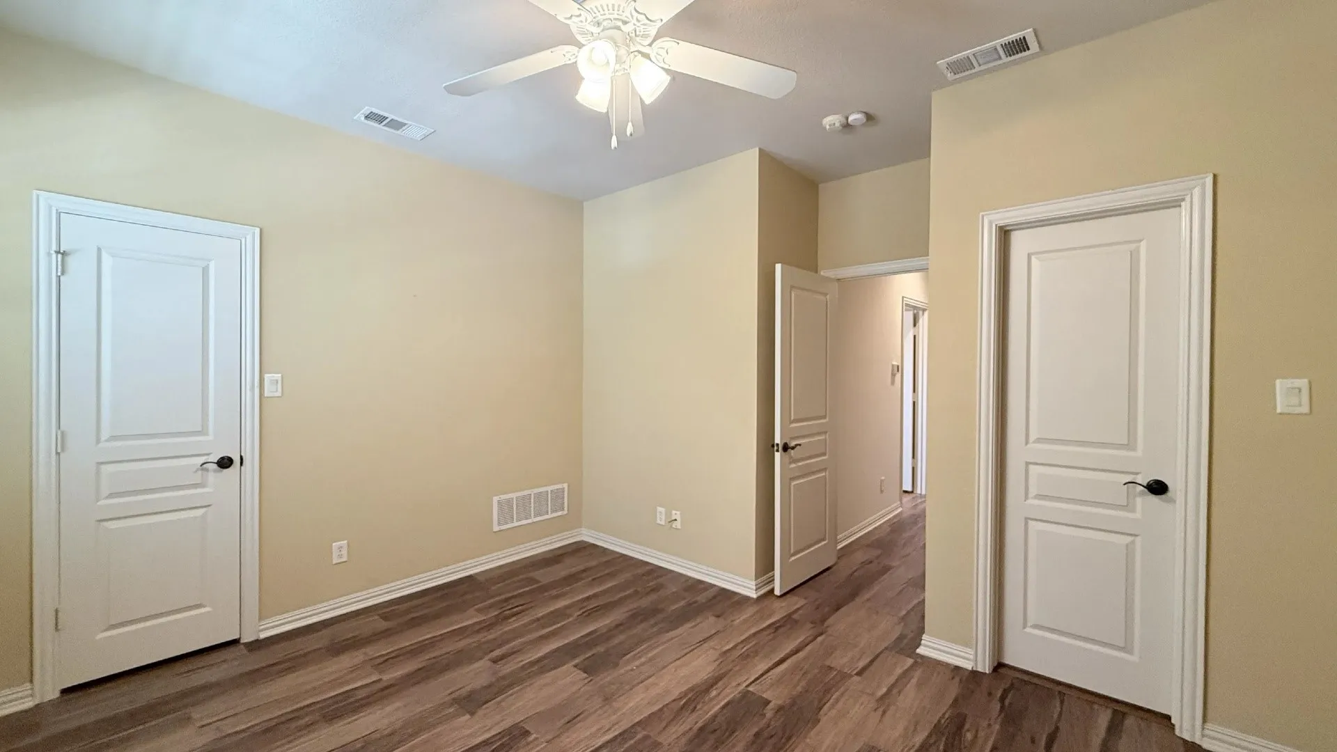 Wood-finish flooring, white paneled doors, ceiling fan with integrated lighting, and neutral wall tones