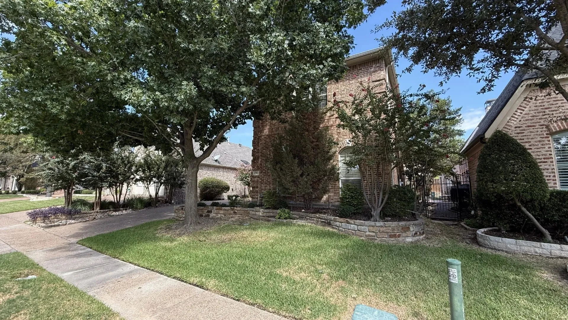 Brick exterior with arched window, stone-finished retaining wall, and mature landscaping