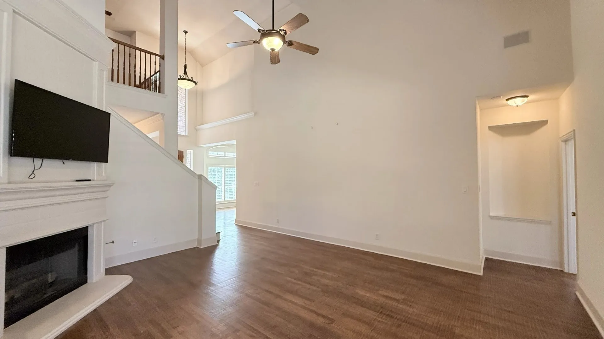 Vaulted ceilings with a ceiling fan, a fireplace with a mantel, wood-finish flooring, and a second-story interior balcony
