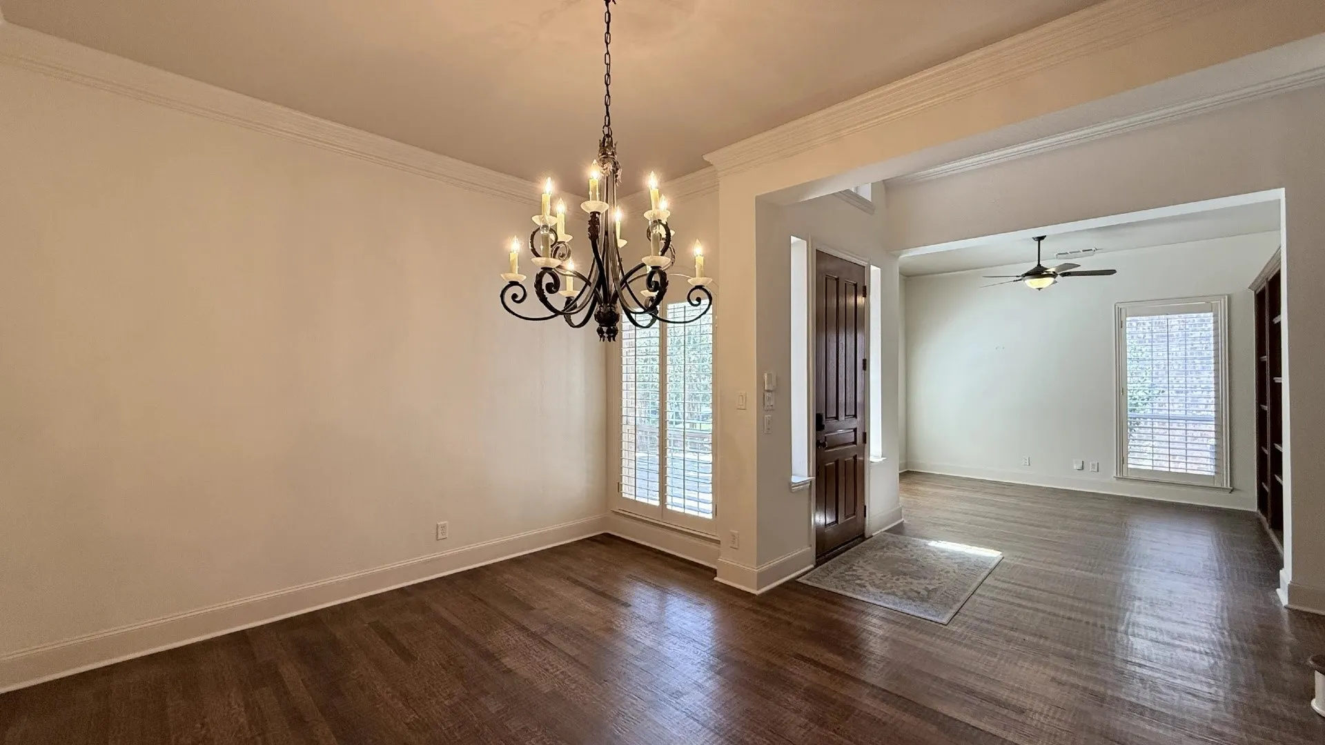 Hardwood flooring, crown molding, wrought iron chandelier, plantation shutters, and built-in shelving