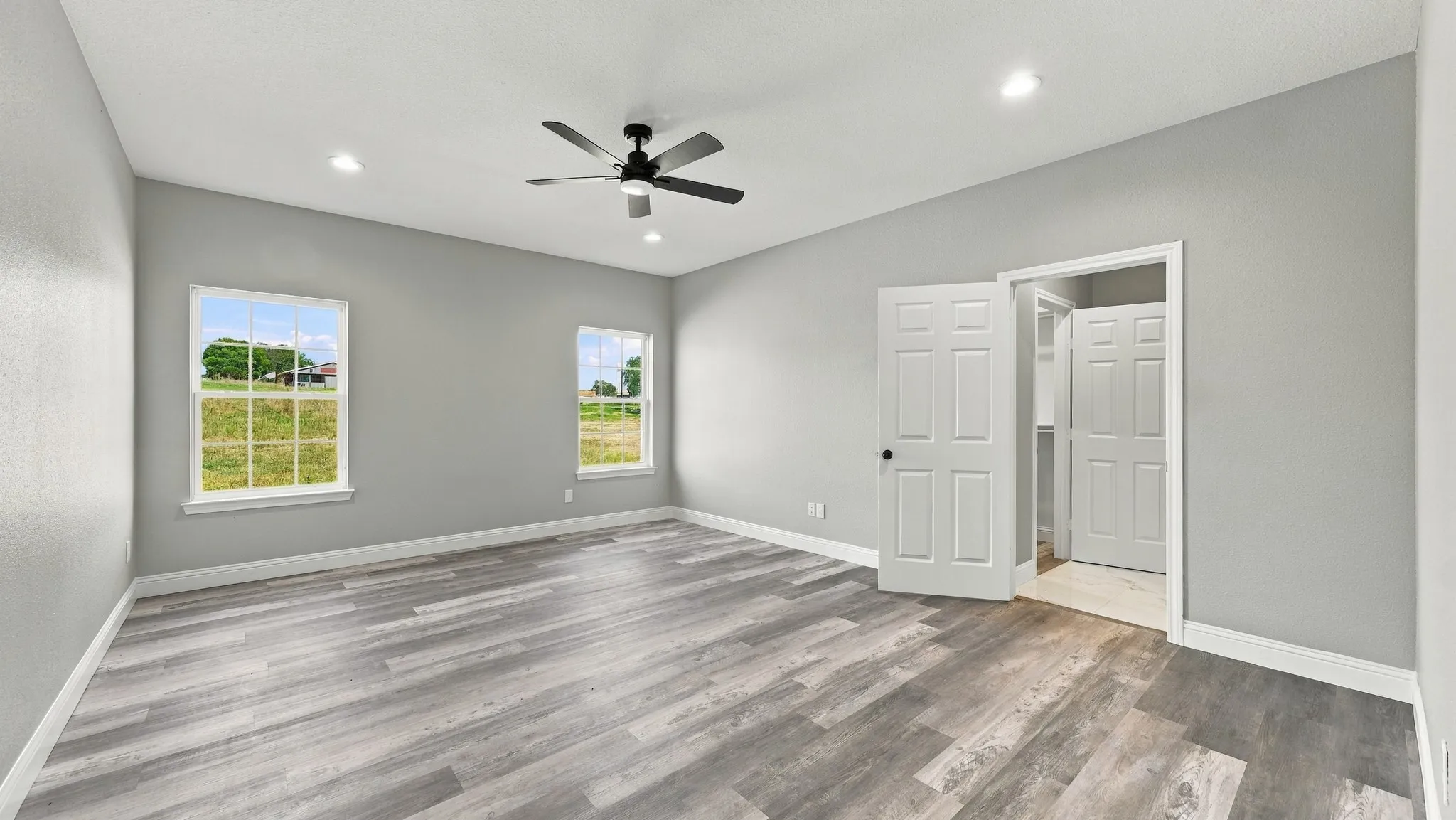 Neutral-toned interior featuring wood-finish flooring, recessed lighting, a ceiling fan, and multi-pane windows