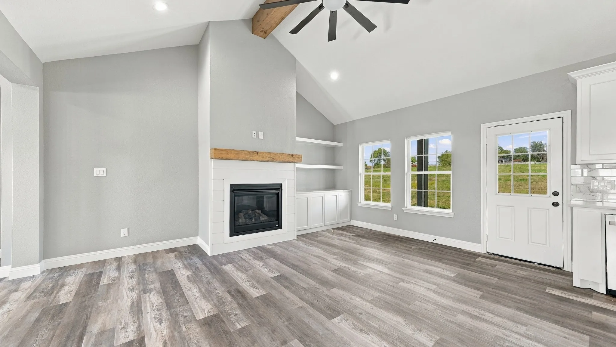 Vaulted ceilings, wood-finish flooring, built-in shelving, fireplace with a wood mantel, and recessed lighting