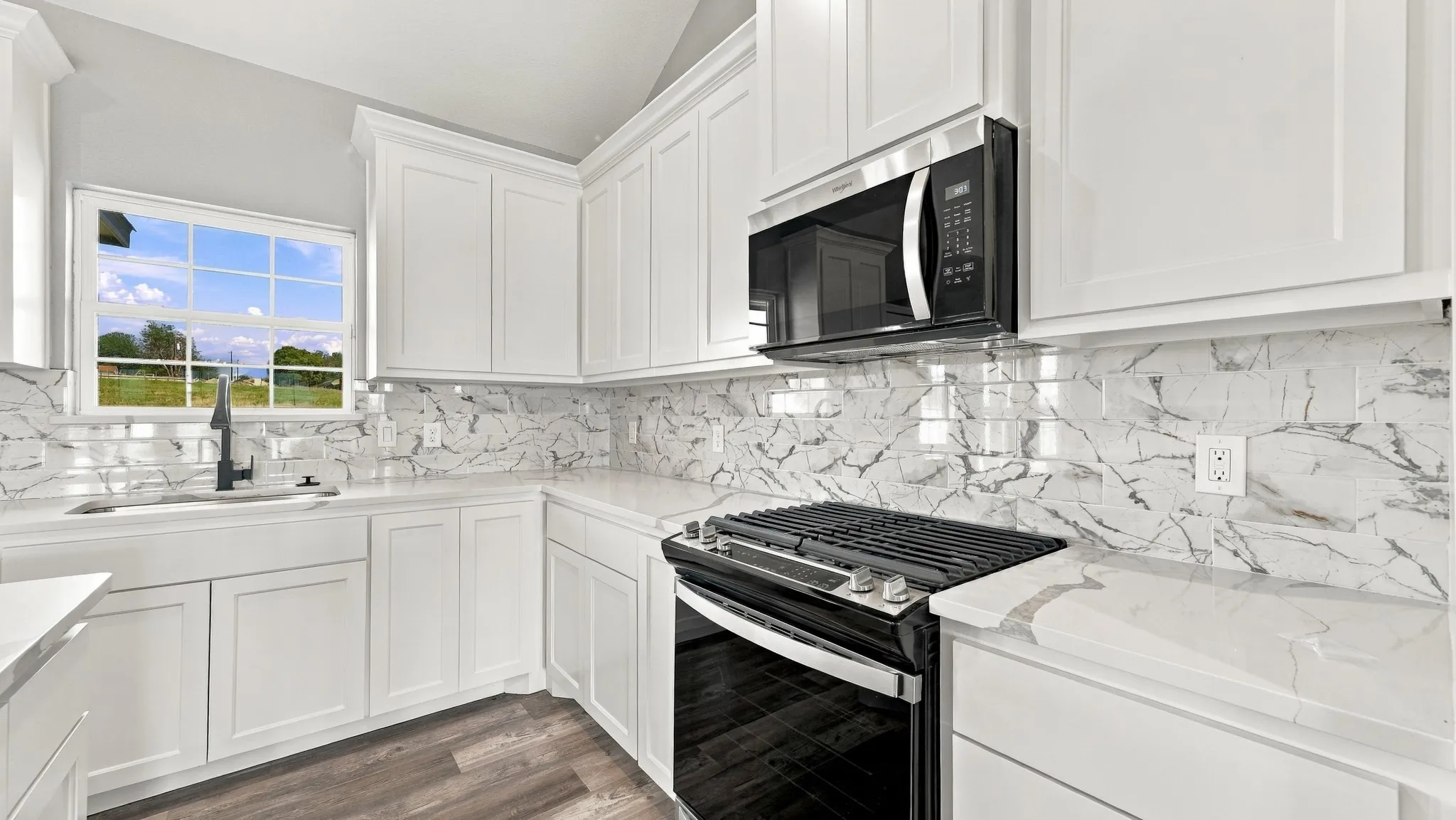 Kitchen featuring white shaker-style cabinetry, patterned tile backsplash, solid-surface countertops, black finish built-in appliances, and wood-finish flooring