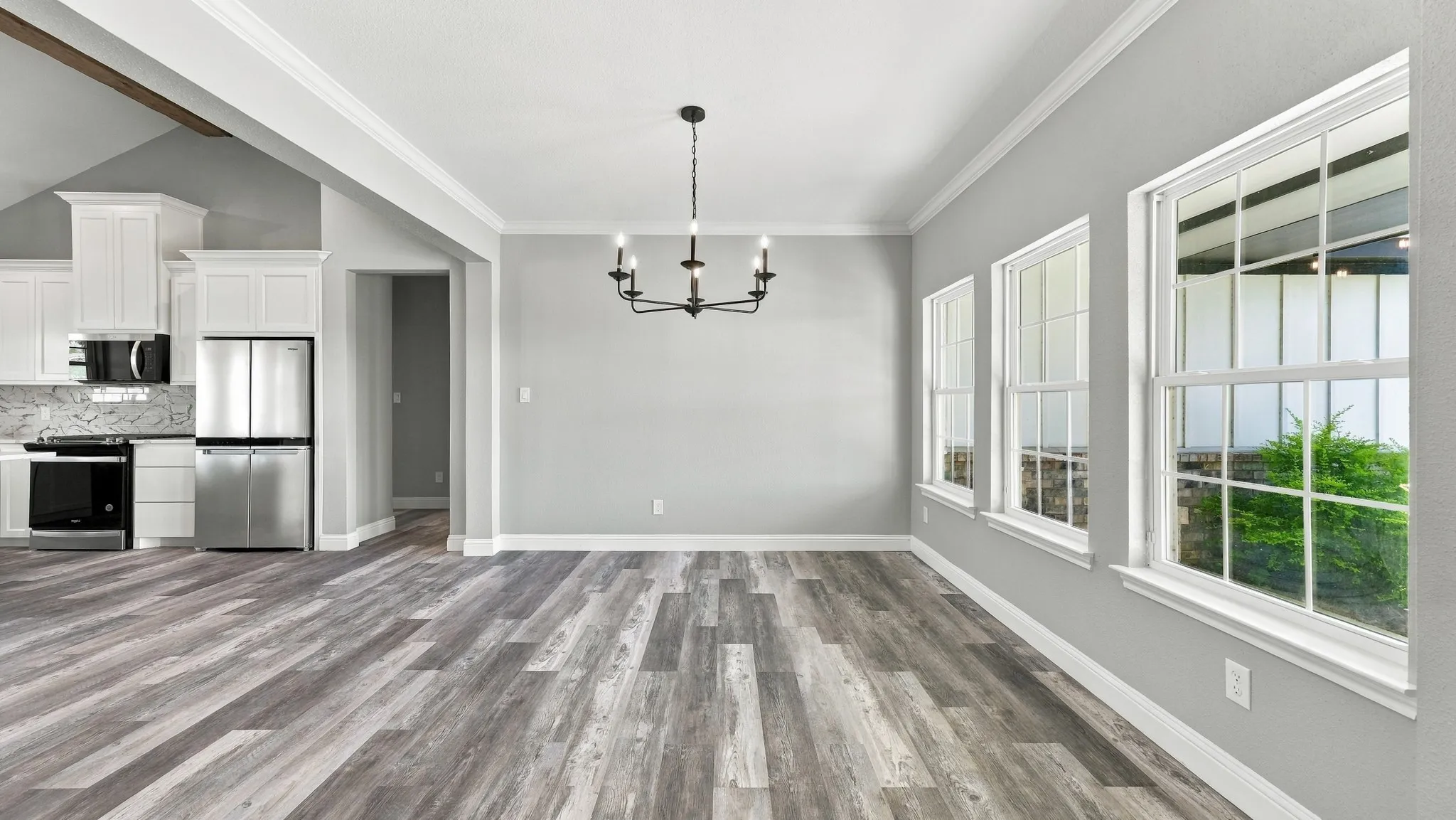 Wood-finish flooring, crown molding, multi-light chandelier, and large windows with pane detailing