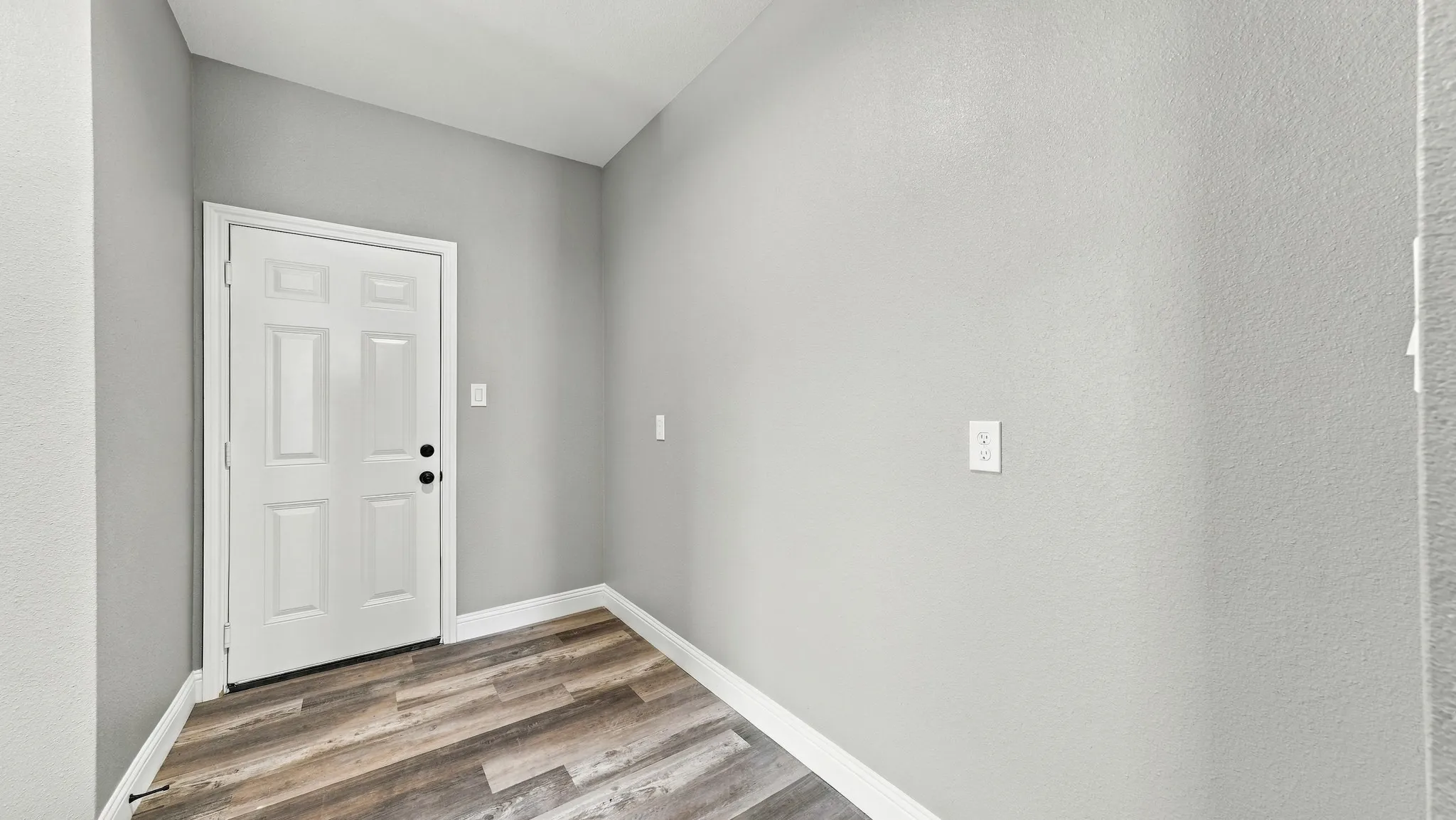 Solid-core interior door with a multi-panel design, neutral interior paint finish, and wood-finish flooring