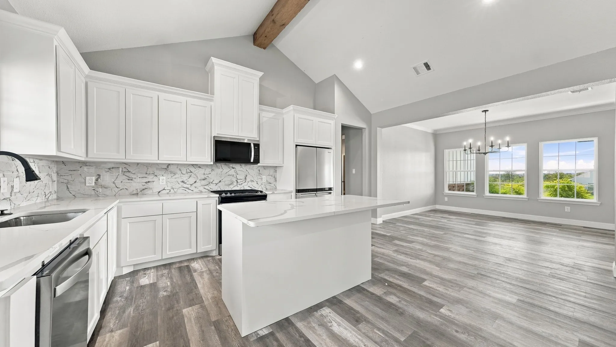 Kitchen featuring white cabinetry, quartz countertops, a stone-patterned backsplash, wood-finish flooring, and a vaulted ceiling with a wooden beam