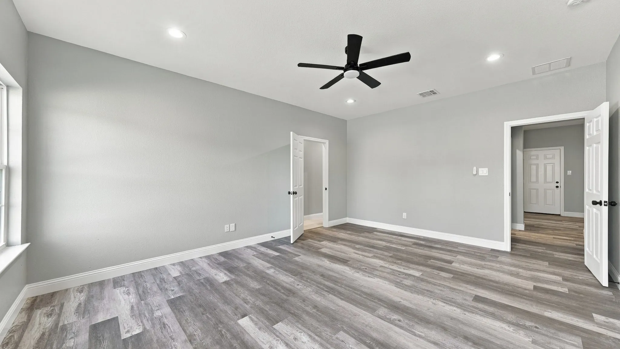 Spacious interior featuring wood-finish flooring, recessed lighting, and a multi-blade ceiling fan