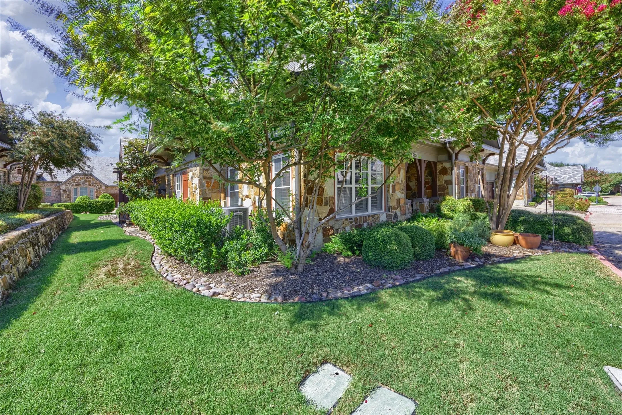 Stunning landscaping with perfectly pruned flower beds and lush grassy area.