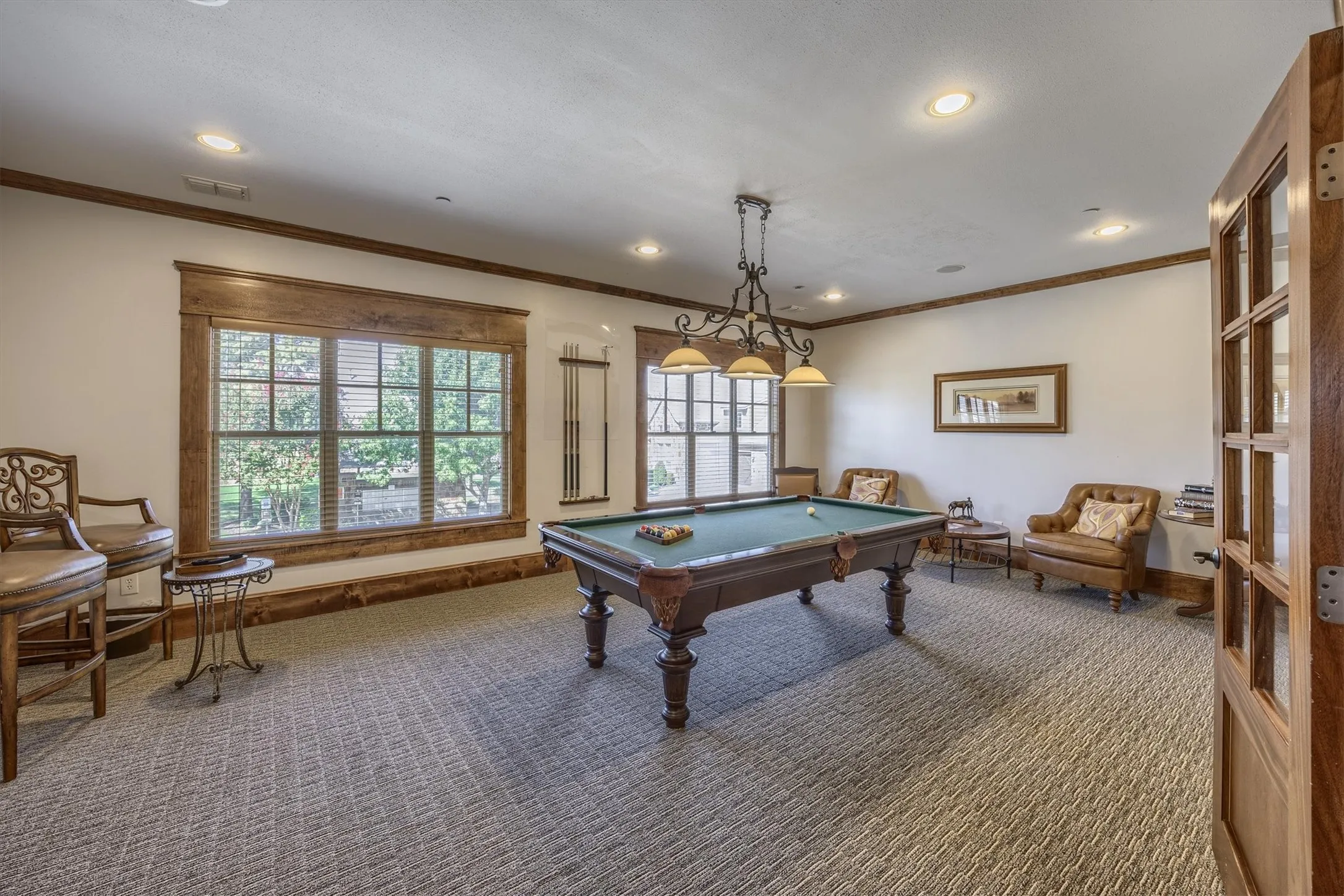 Recessed lighting, wood-trimmed windows, patterned carpeting, wood-frame door, and a multi-light chandelier