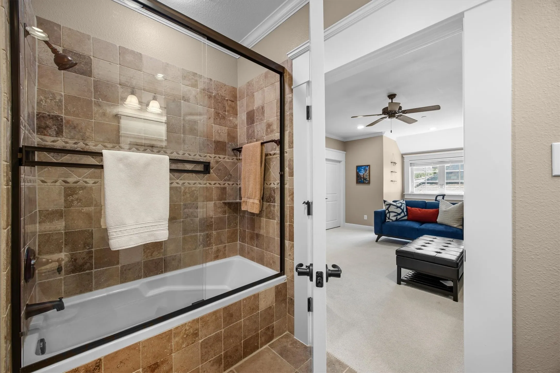 Beautiful glass sliding shower doors and tumbled tile surround with access into the guest quarters or 3rd bedroom of the home.