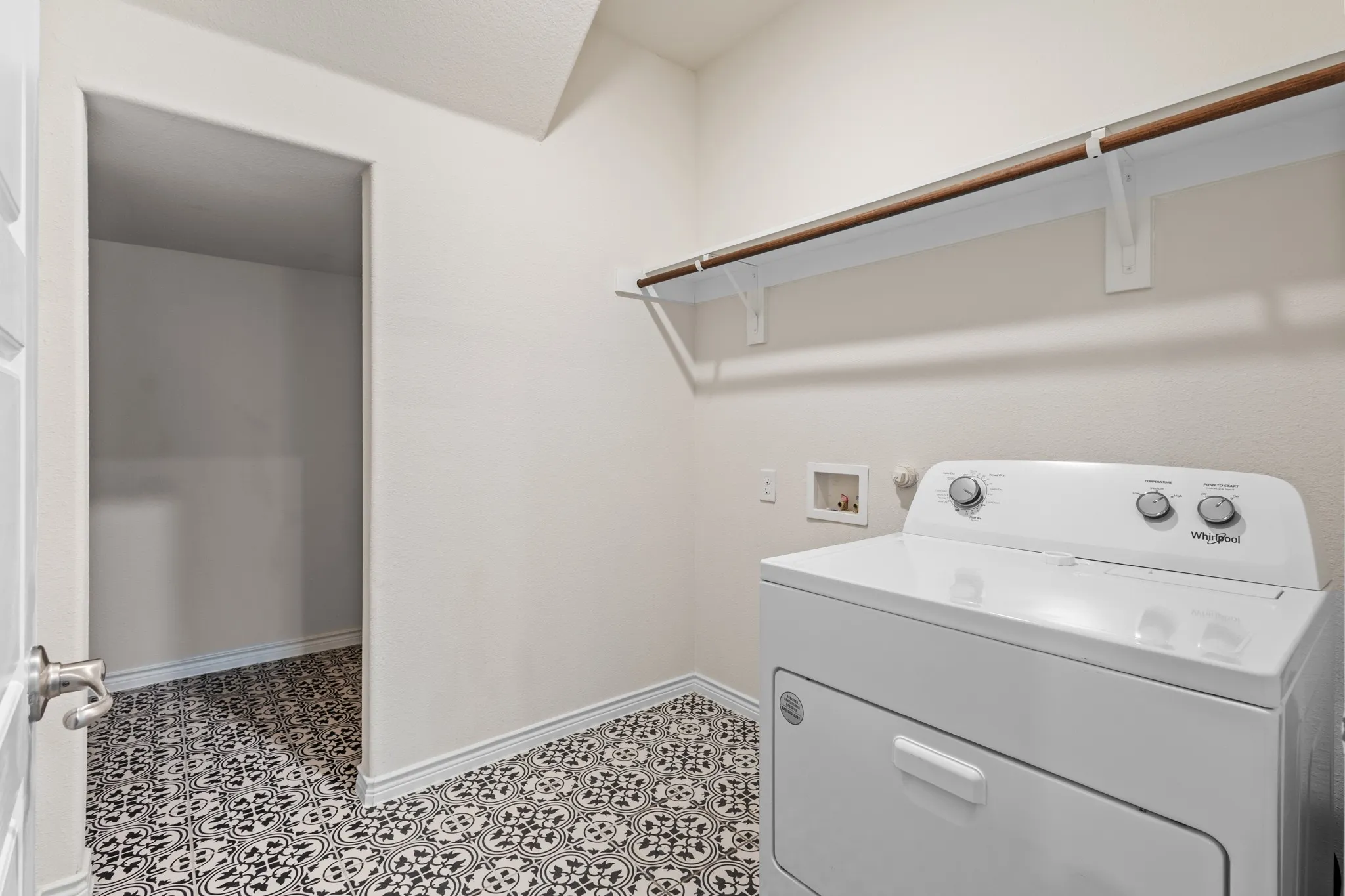 Utility area featuring patterned tile flooring, built-in shelving, and a clothing rod