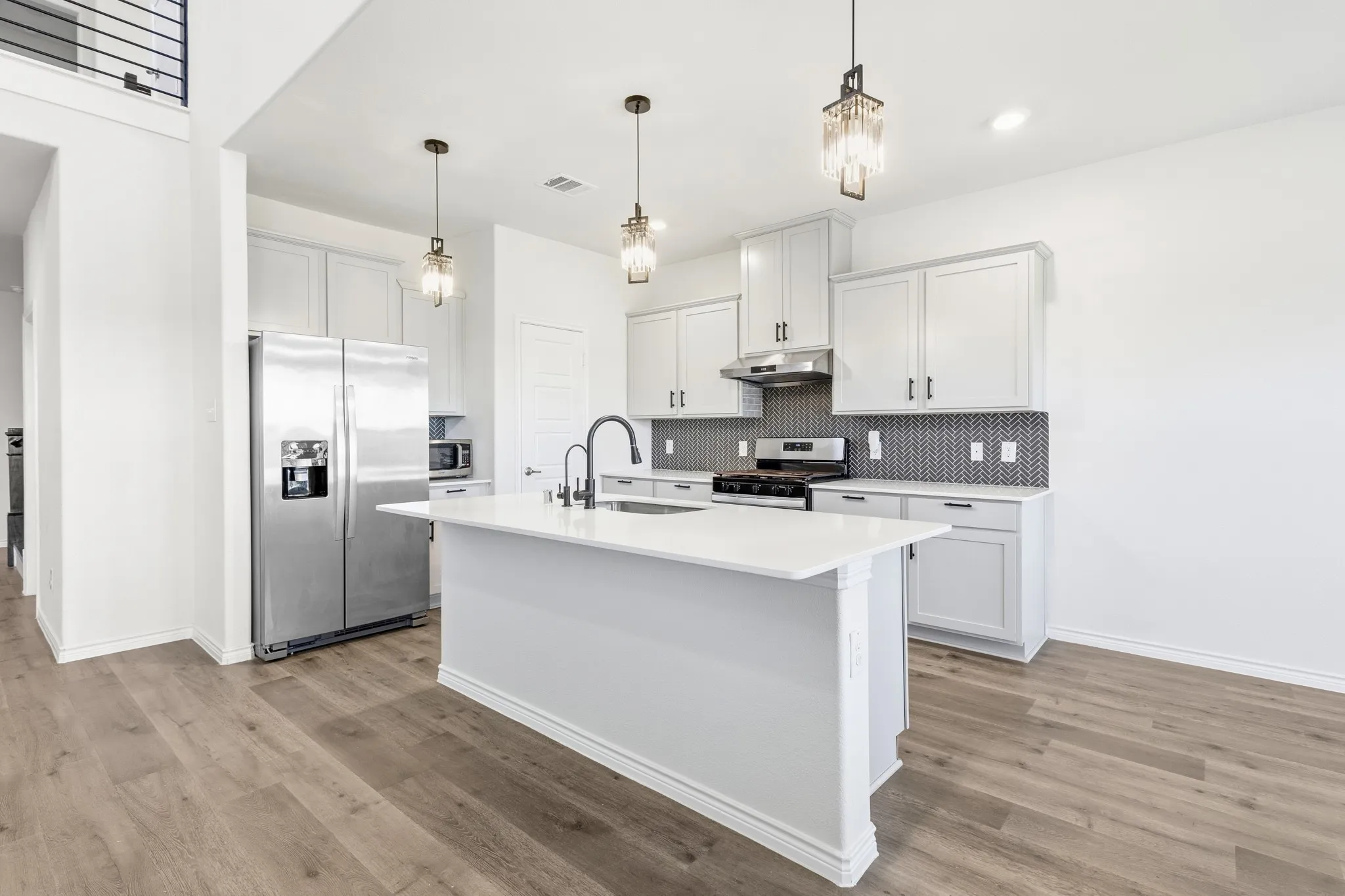 White kitchen cabinetry with black hardware, stainless steel appliances, and a mosaic tile backsplash
