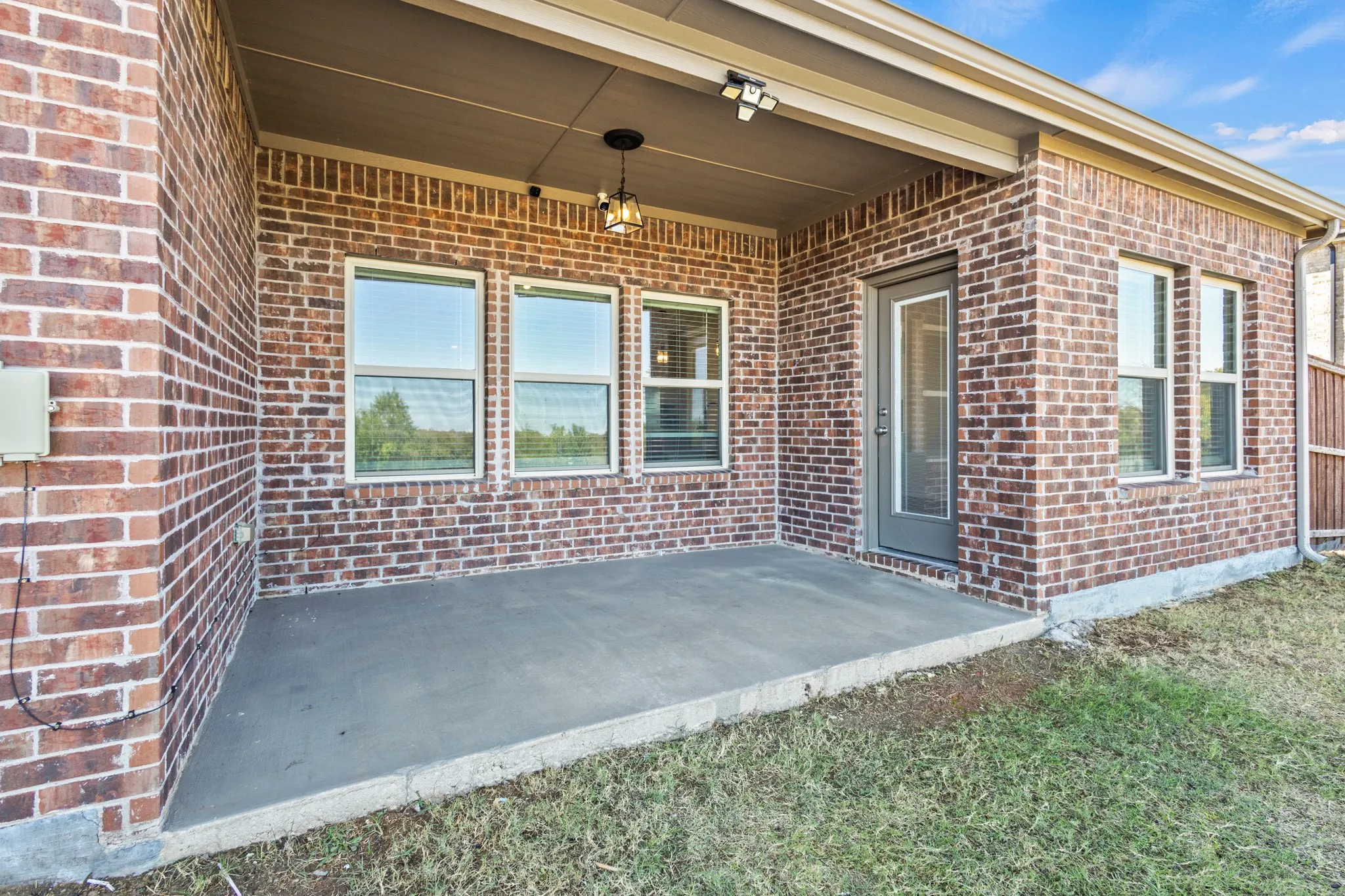 Covered concrete patio with brick exterior and multiple windows