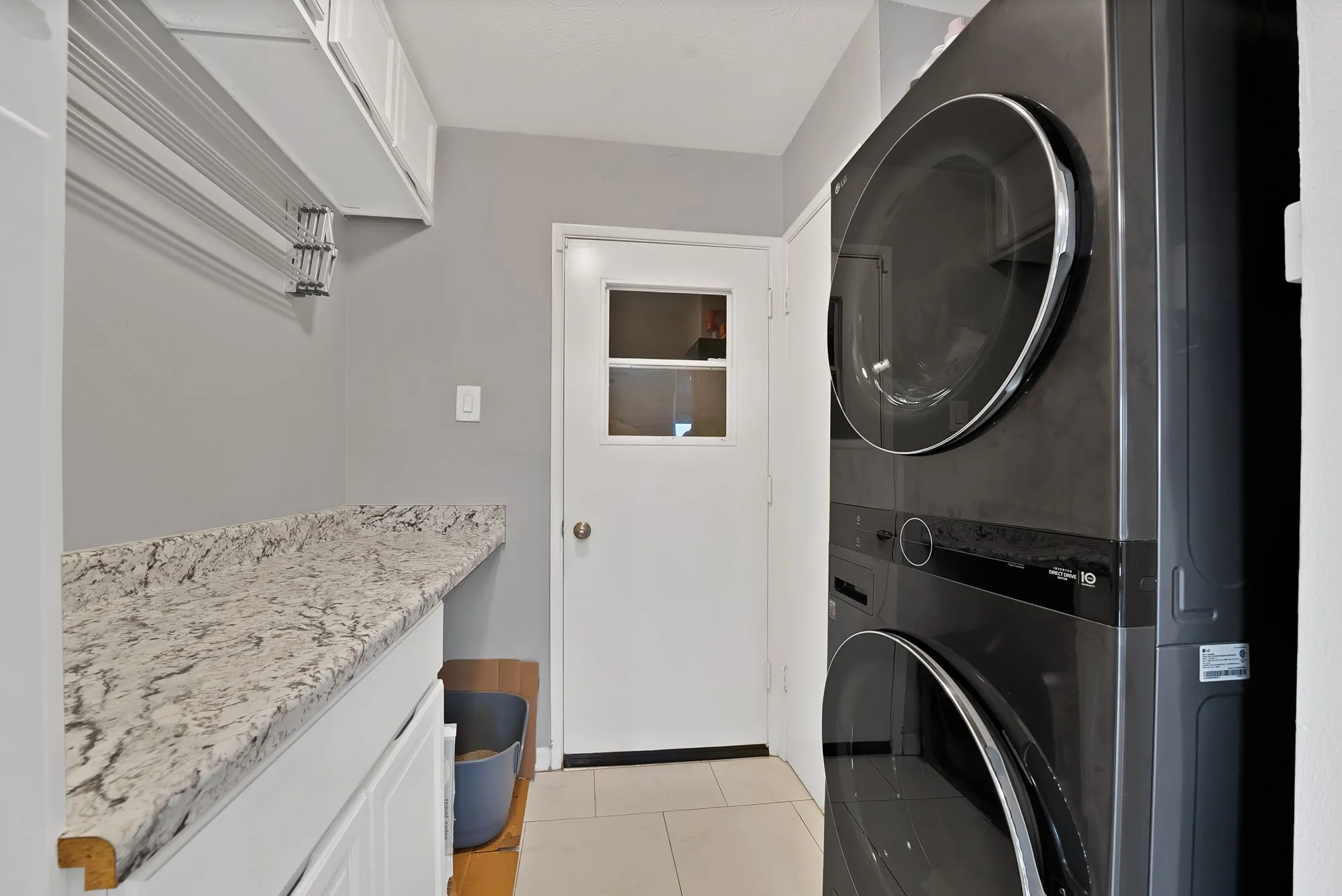 Laundry room featuring light tile patterned floors and stacked washer and clothes dryer