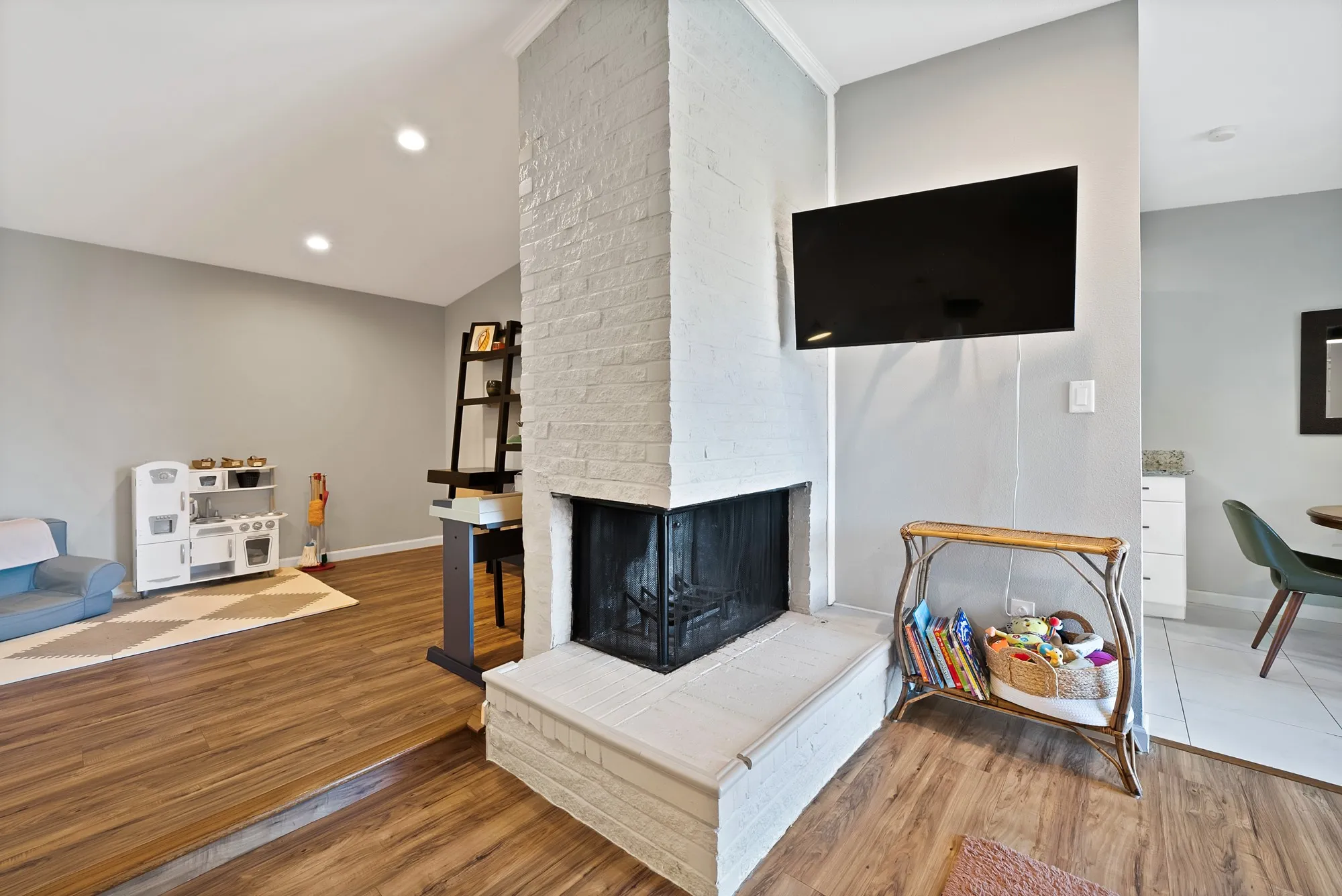 Living area with lofted ceiling, wood finished floors, a brick fireplace, and recessed lighting