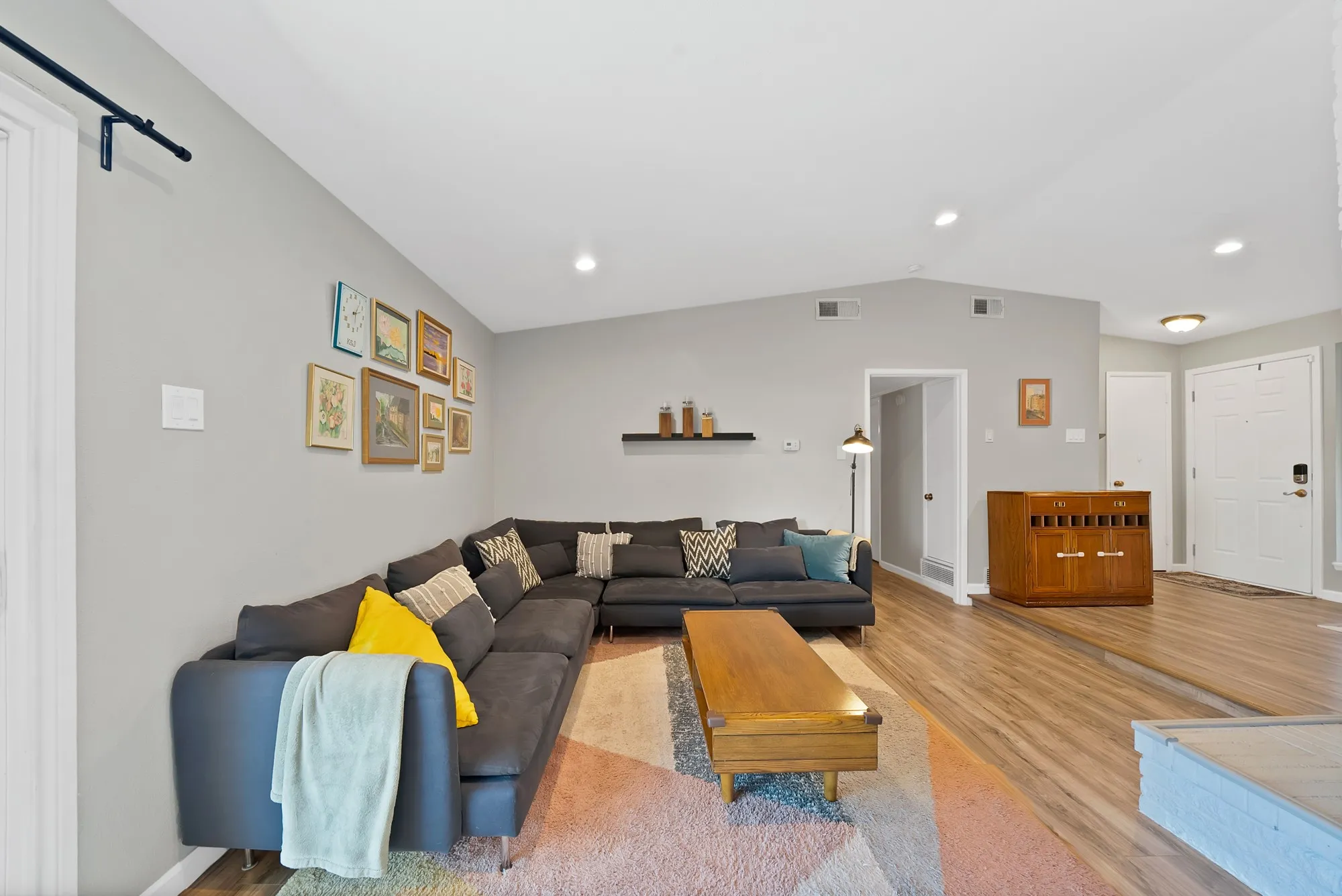 Living room with recessed lighting, vaulted ceiling, and wood finished floors