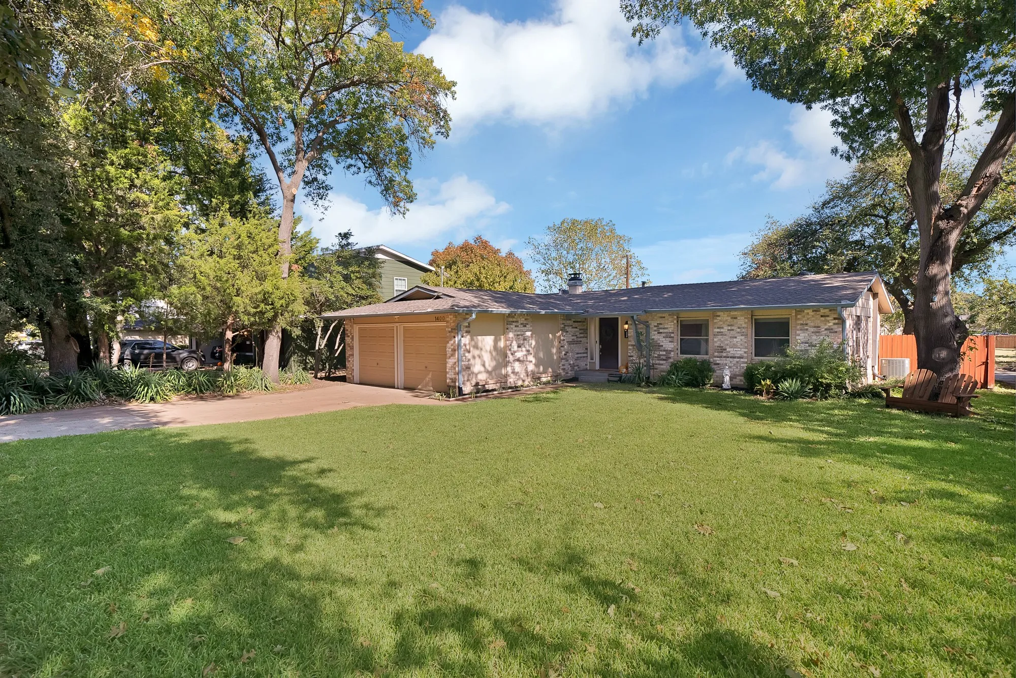 View of front of home with concrete driveway, a front lawn, brick siding, and an attached garage