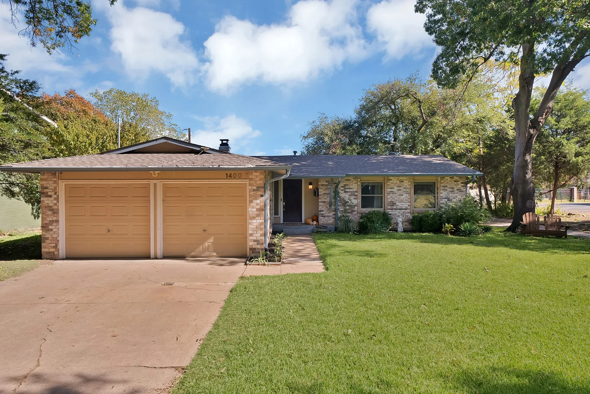 View of front of property featuring a front yard, brick siding, a garage, concrete driveway, and a shingled roof