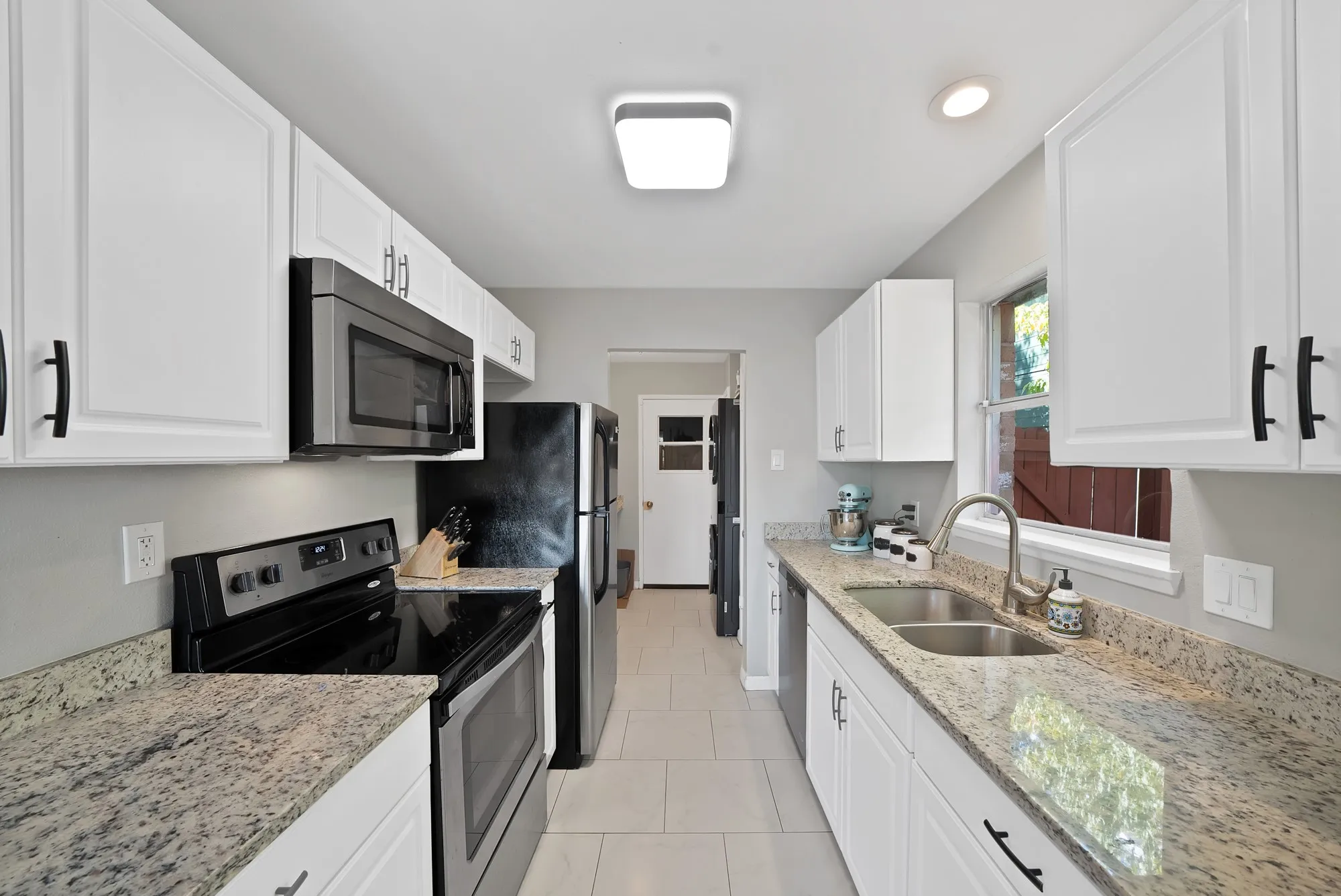 Kitchen featuring stainless steel appliances, light stone countertops, white cabinetry, light tile patterned floors, and recessed lighting