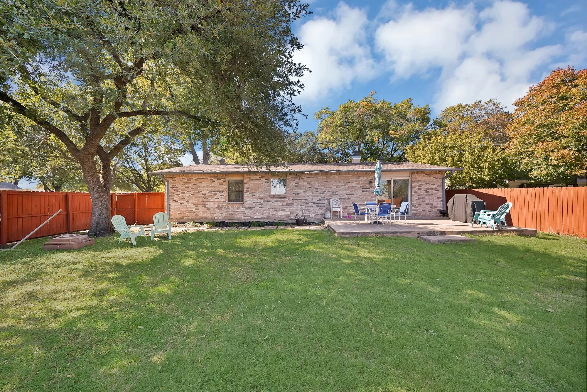Back of house with a fenced backyard, brick siding, and a wooden deck
