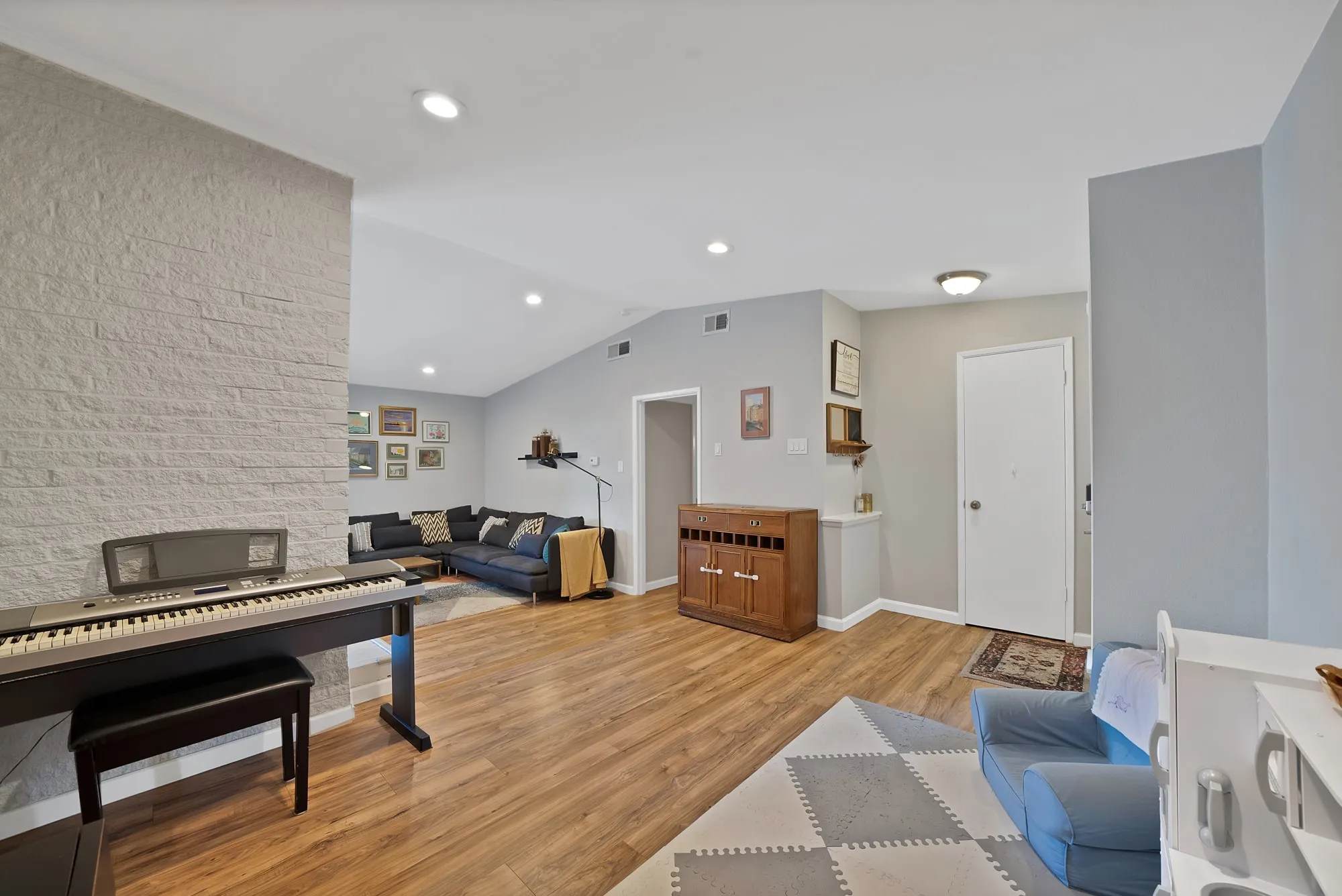 Living room featuring vaulted ceiling, light wood finished floors, and recessed lighting