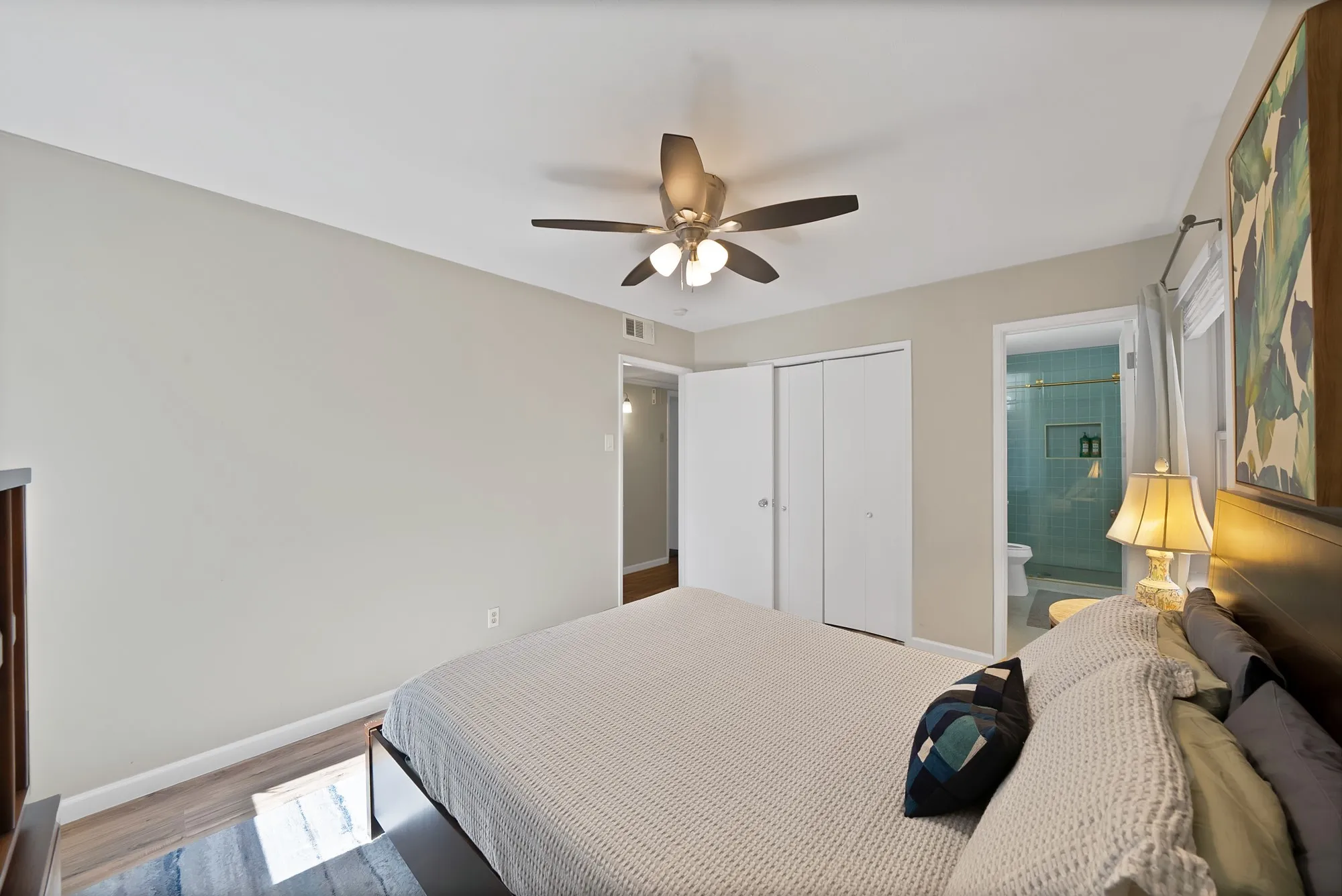 Bedroom with ceiling fan, a closet, wood finished floors, and connected bathroom