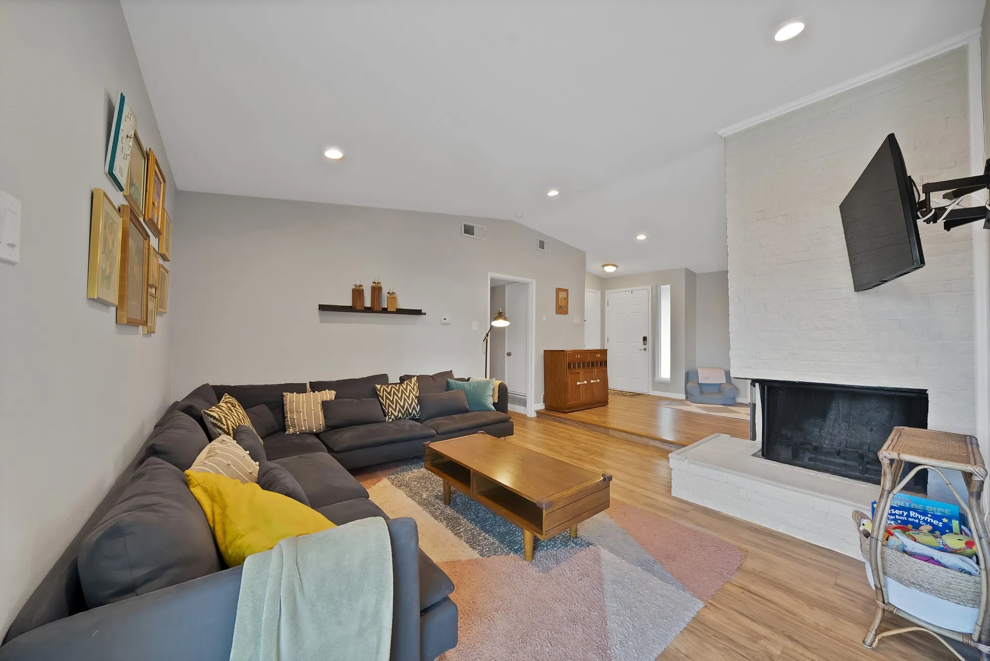 Living area featuring vaulted ceiling, wood finished floors, a multi sided fireplace, and recessed lighting