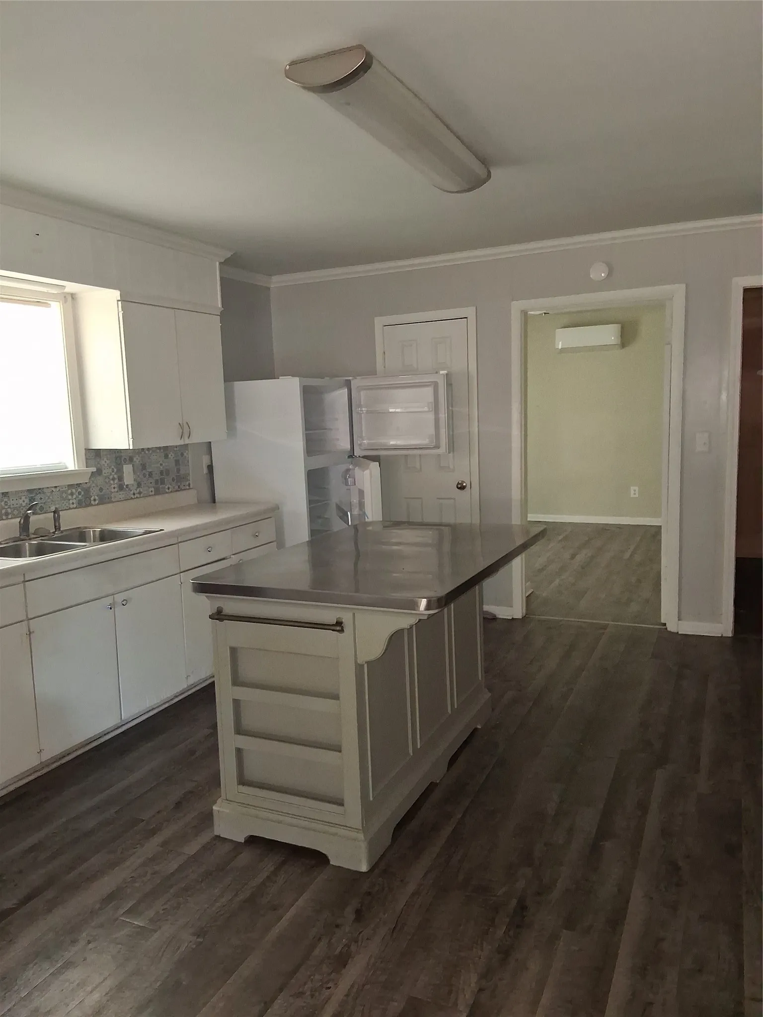 Kitchen featuring white cabinetry, light-toned countertops, a patterned backsplash, and wood-finish flooring