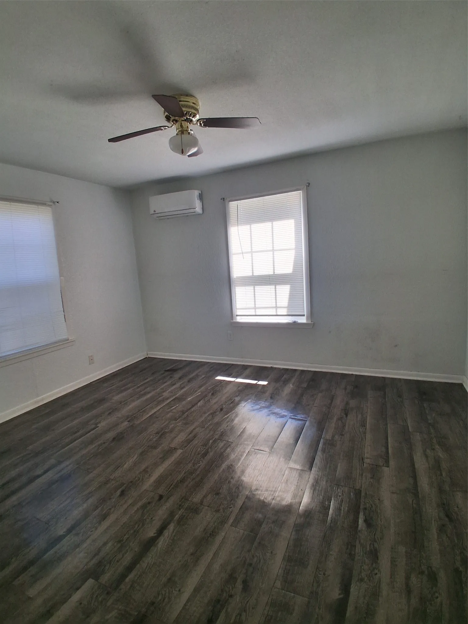 Wood-finish flooring, ceiling fan, and two windows with blinds