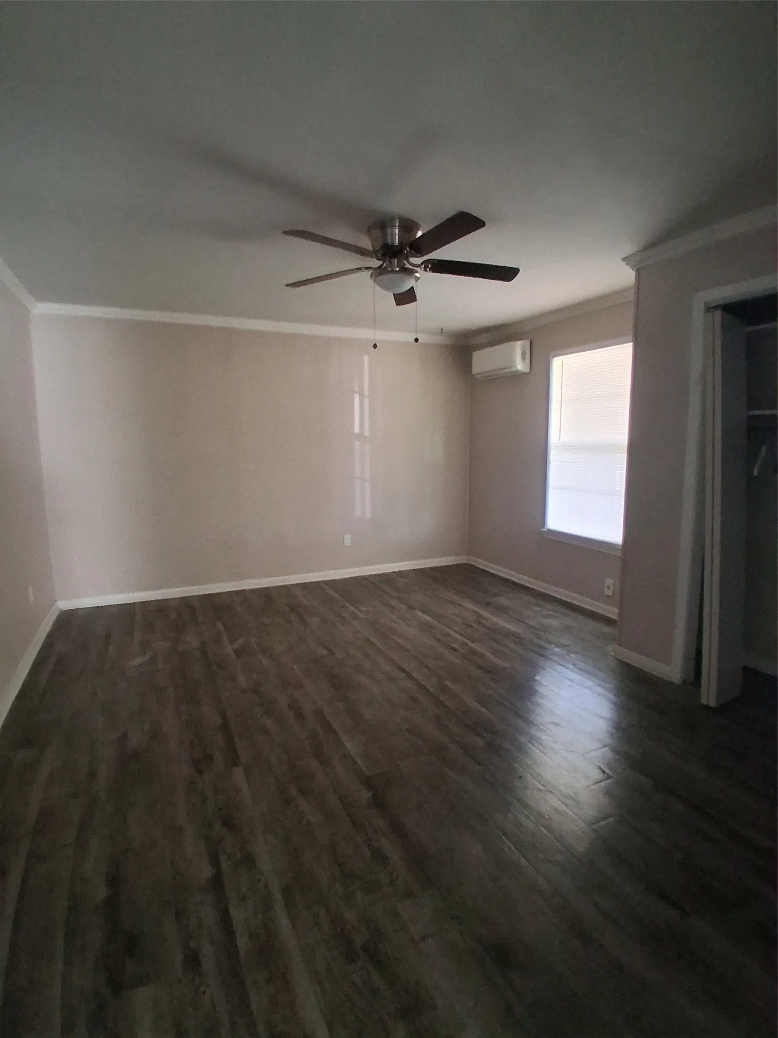 Wood-finish flooring with a ceiling fan, crown molding, and mini-split air conditioning unit