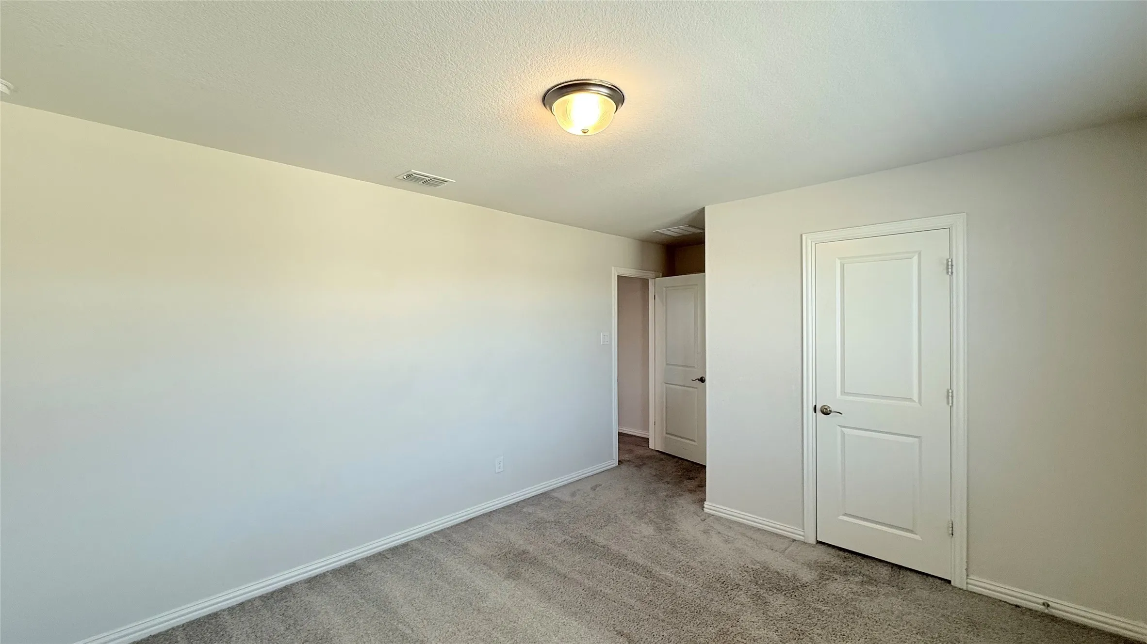 Neutral wall paint, textured ceiling, gray carpet flooring, flush-mount ceiling light